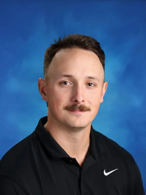 Portrait of a man wearing a black polo shirt against a blue background