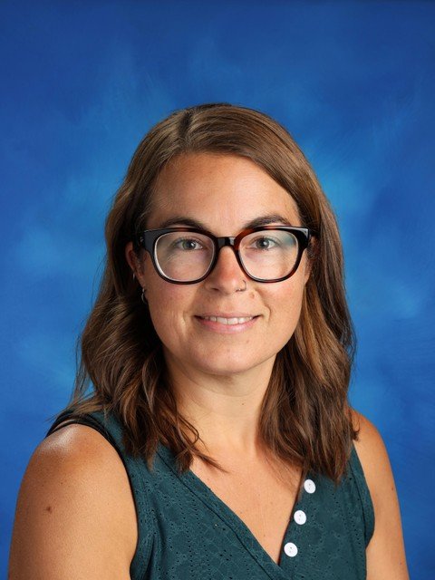 Portrait of a smiling woman with glasses against a blue studio background