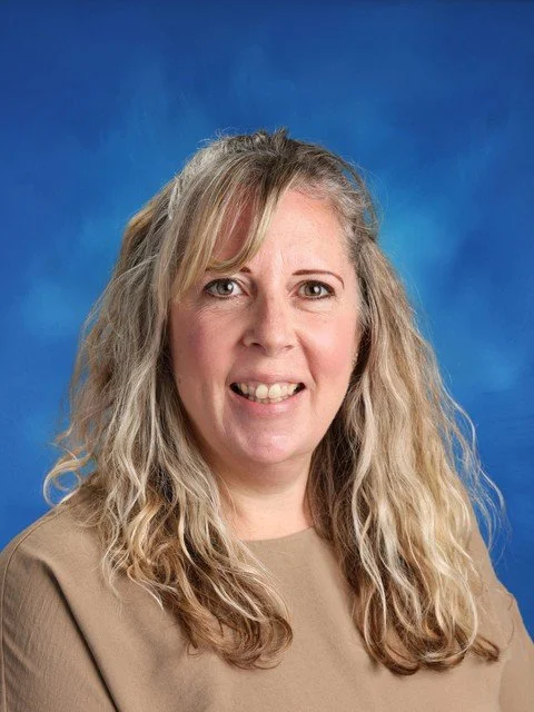Portrait of a smiling blonde woman with long wavy hair against a blue background