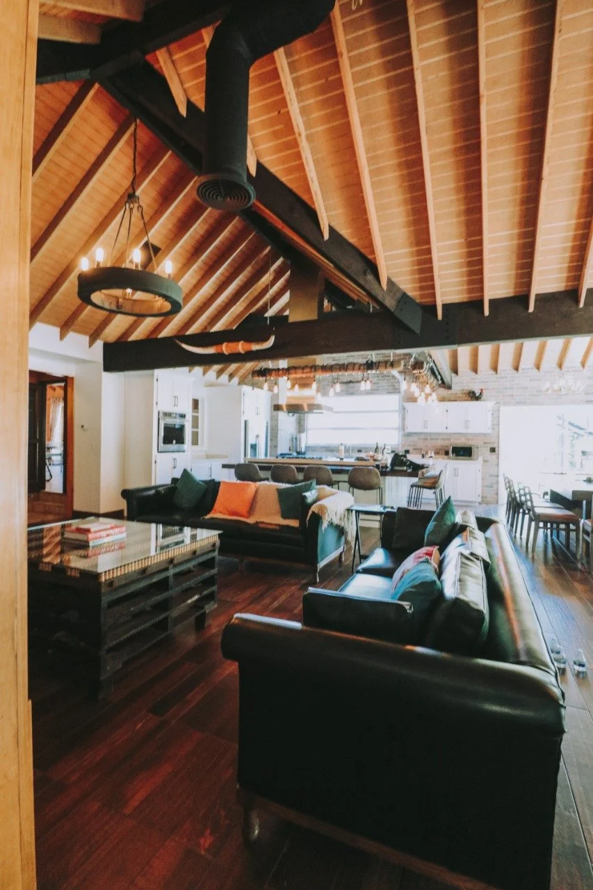 Open-concept living room and fully equipped kitchen with a vaulted wooden ceiling. 