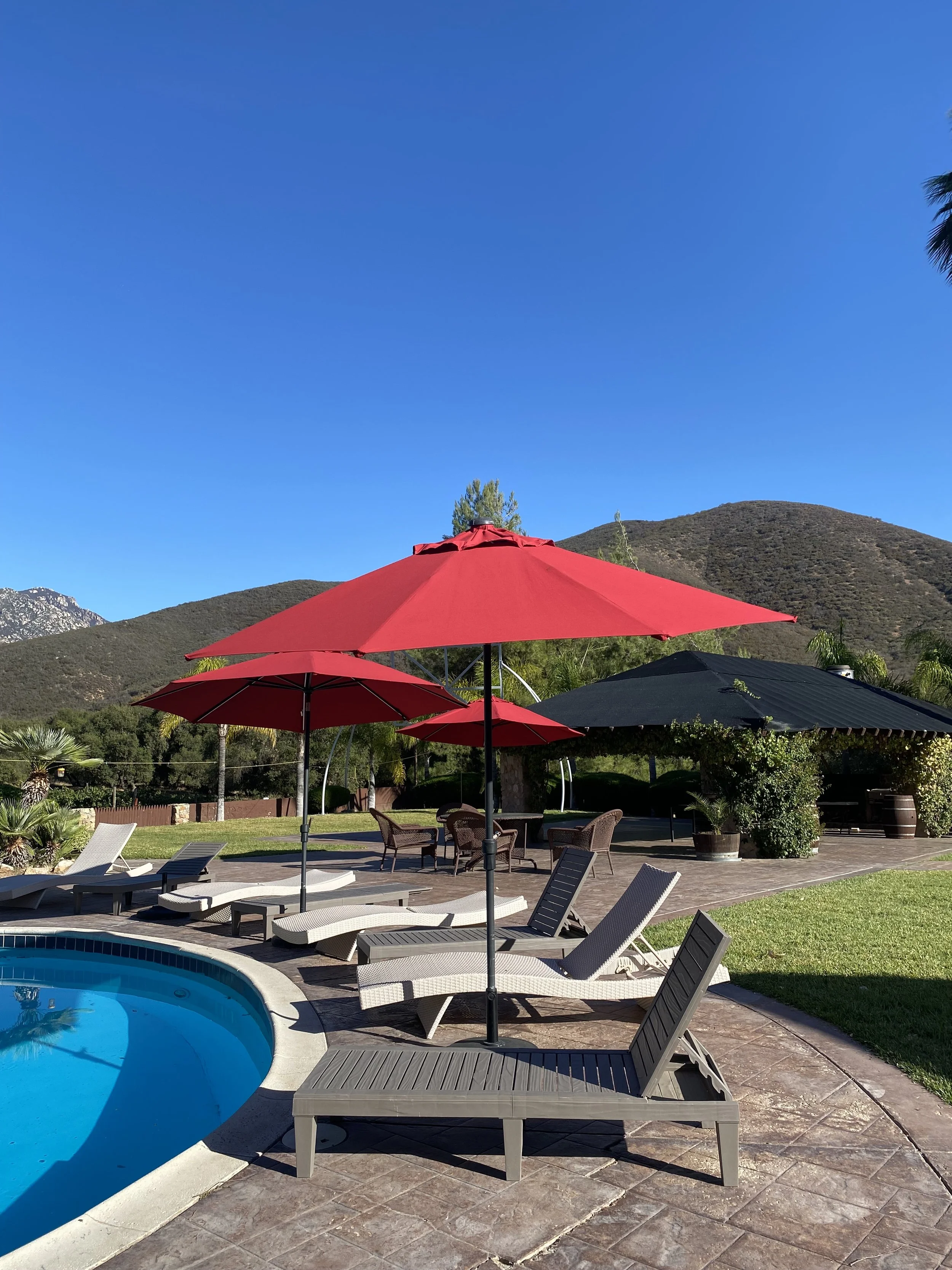 Private pool area with several lounge chairs and red umbrellas, surrounded by stunning views all around.