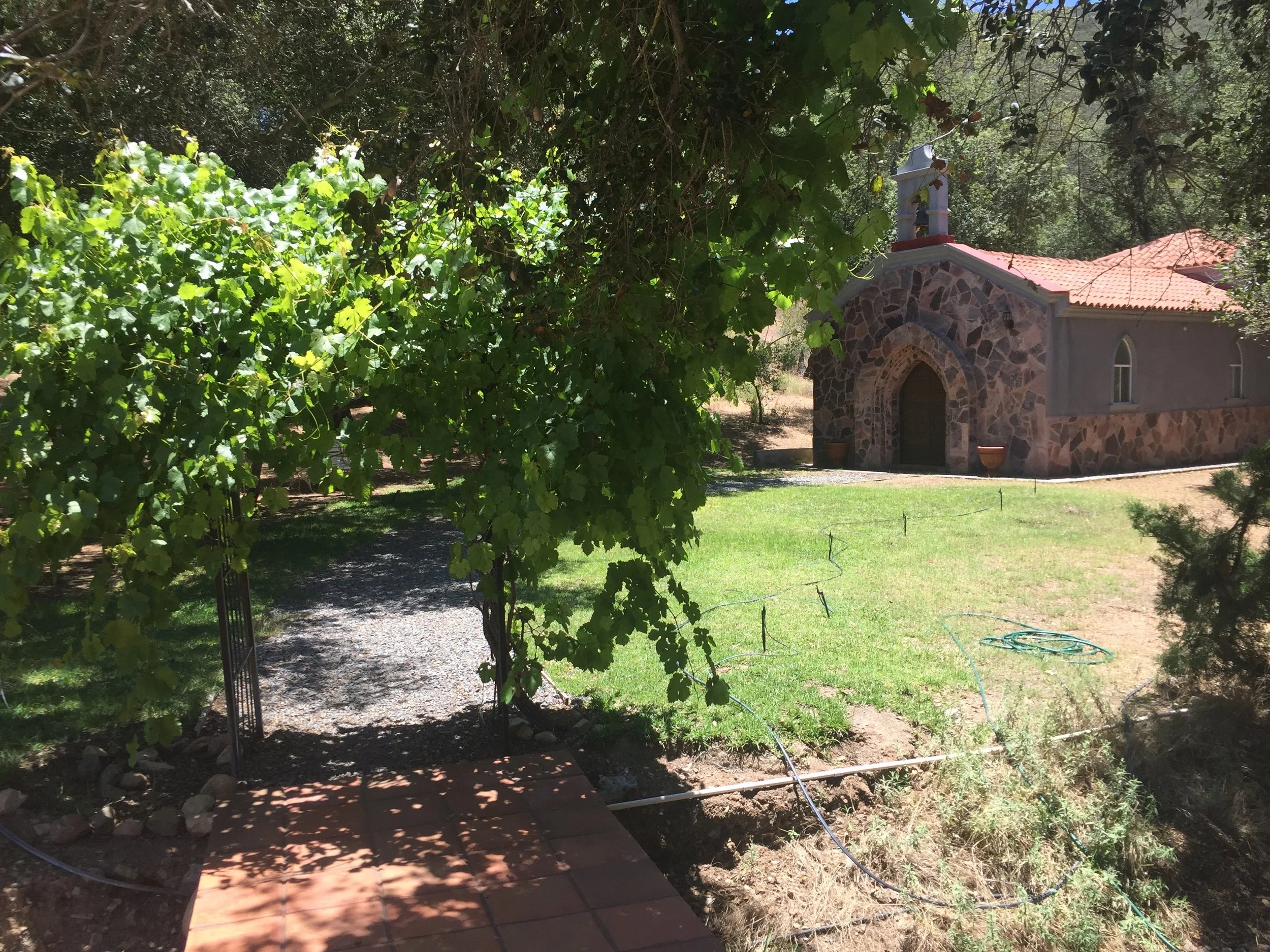 Private stone chapel surrounded by oak trees, with a gravel path leading to it.