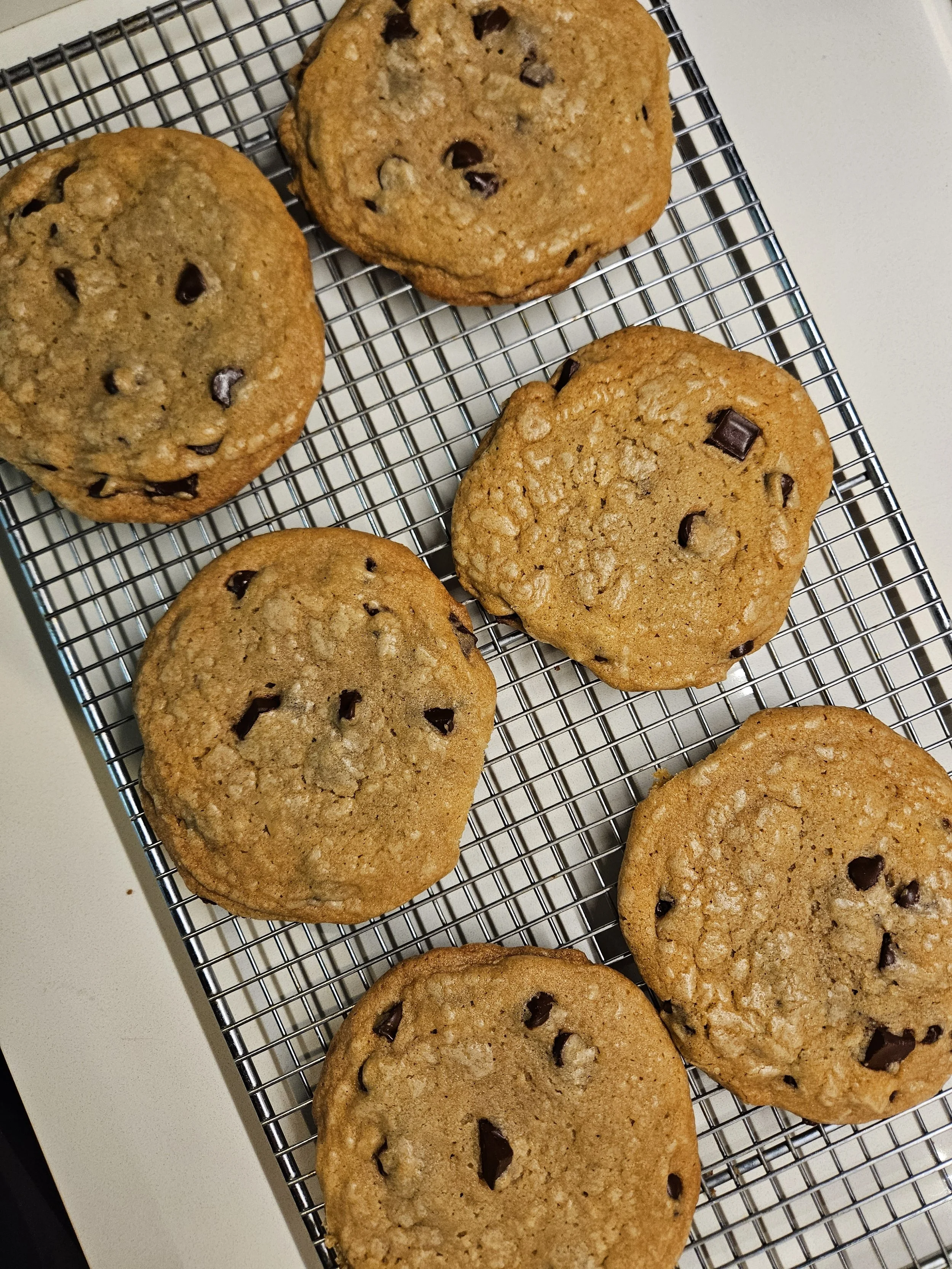 Several chocolate chip cookies cooling on a wire rack. The cookies are golden brown with visible chocolate chunks.