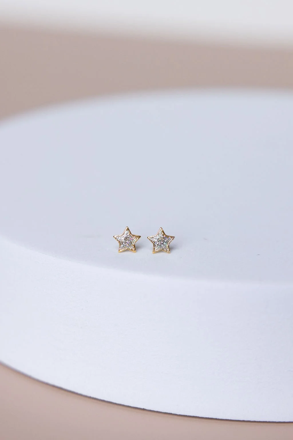 Star-shaped stud earrings with sparkling stones on a white surface.