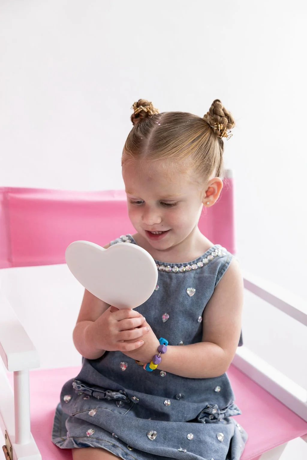 young girl looking at new ear piercing in mirror