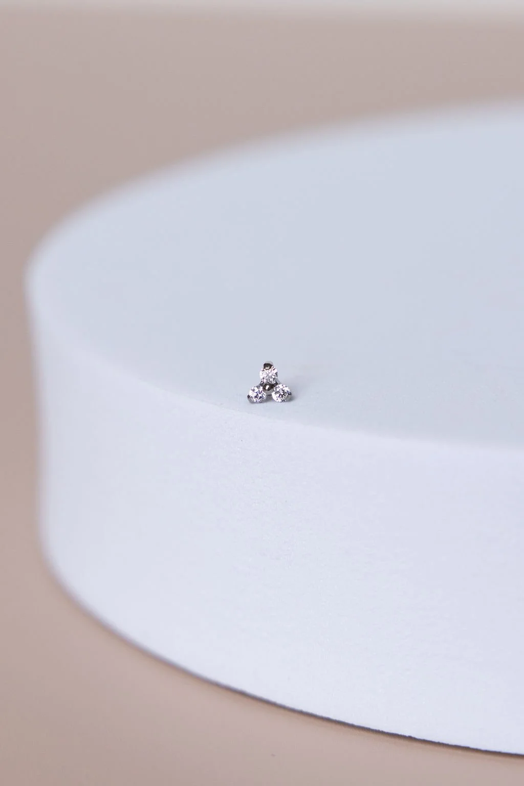 Close-up of small diamond studs on a white curved surface with beige background.