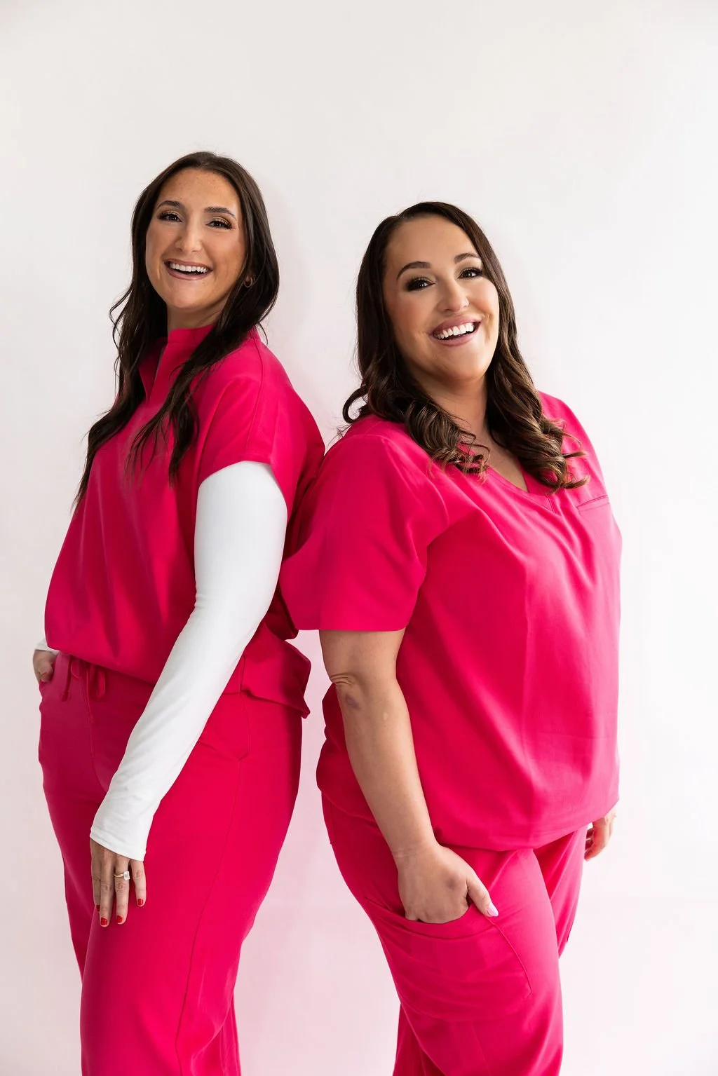 two nurses standing back to back in pink scrubs