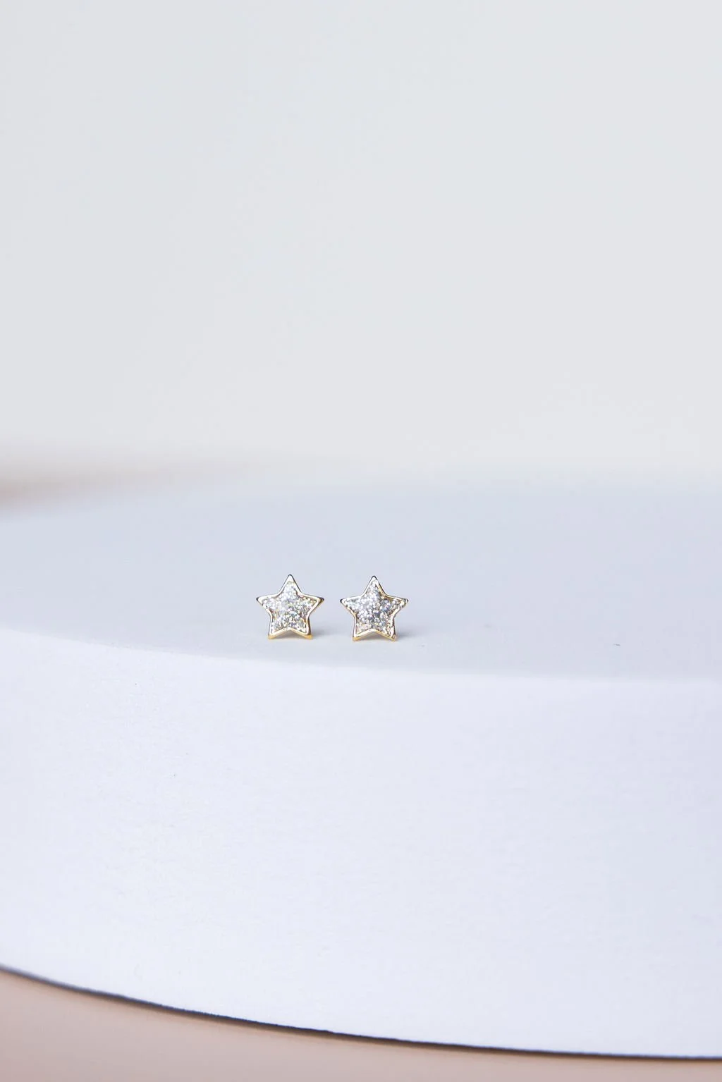 Star-shaped earrings with small diamonds on a white surface