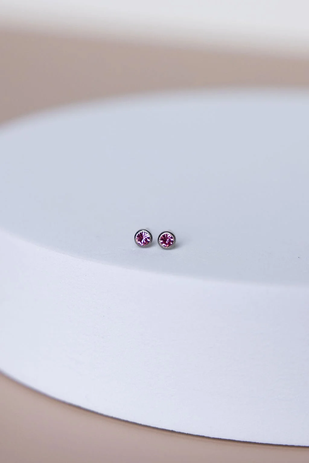 Pair of small pink gemstone stud earrings on a white surface.