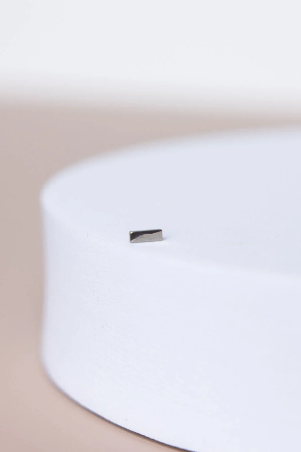 Close-up of a small metallic chip on a smooth white surface.