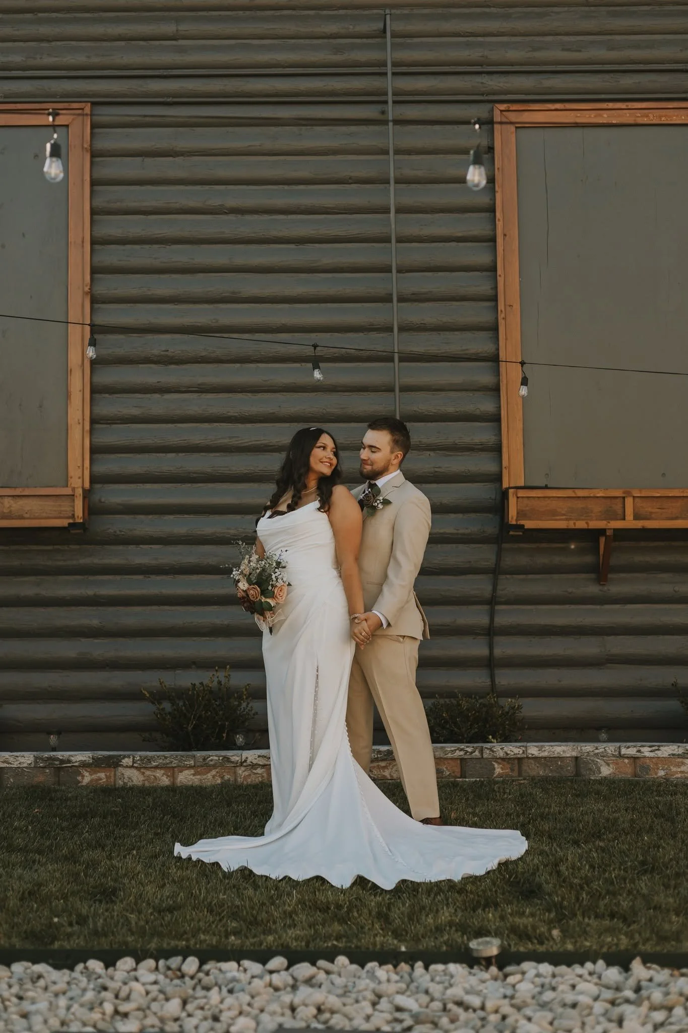Laurie’s customers, Mariana and Carmen holding hands on a green lawn on their wedding day.