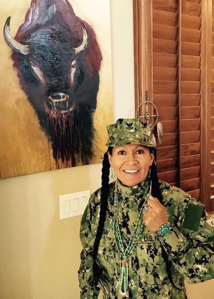 A woman in military uniform standing indoors next to a large painting of a bison on the wall.