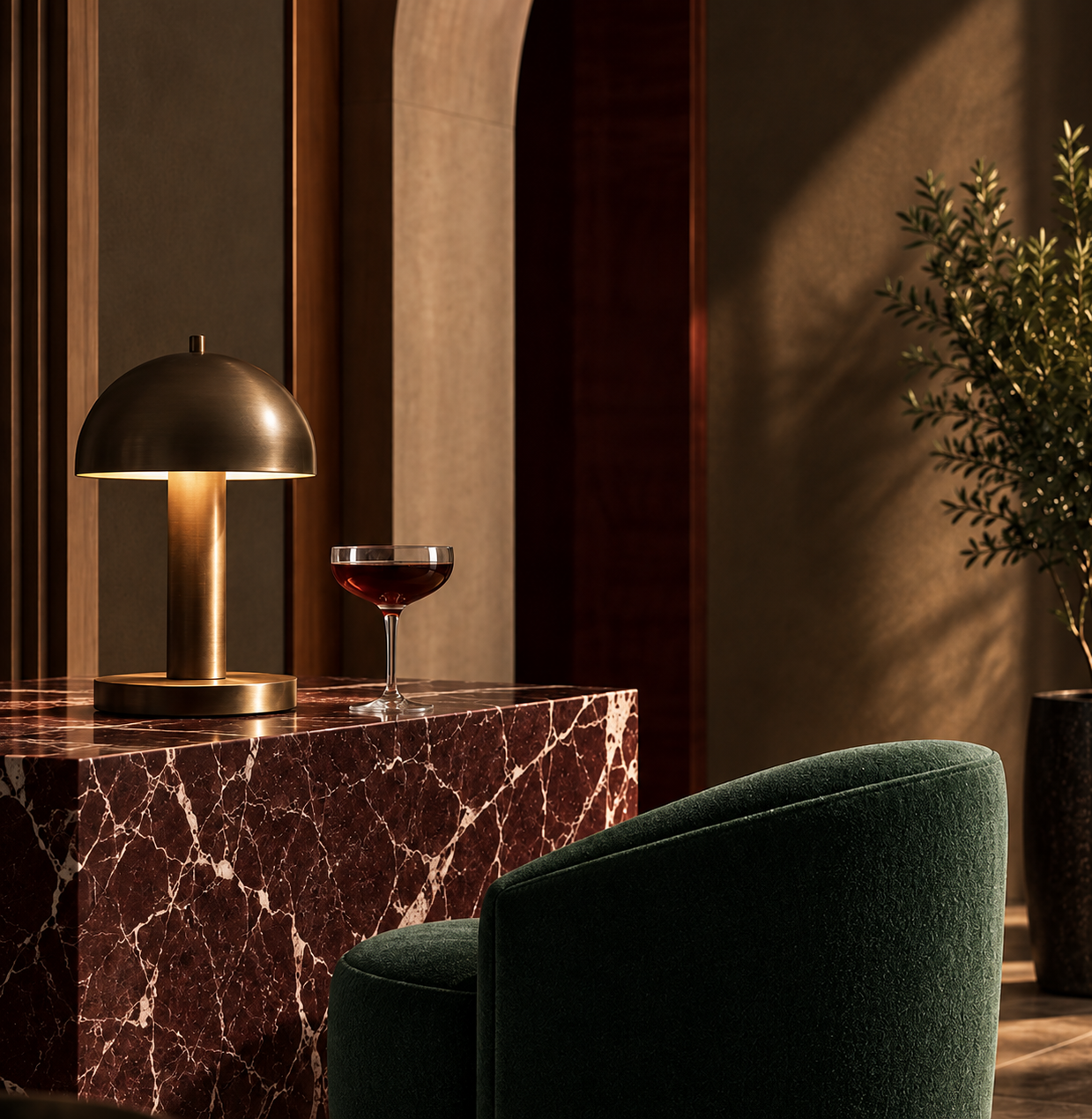 A modern interior with a red marble table, a gold table lamp, a glass of red wine, a green velvet chair, and a potted plant, with warm ambient lighting.