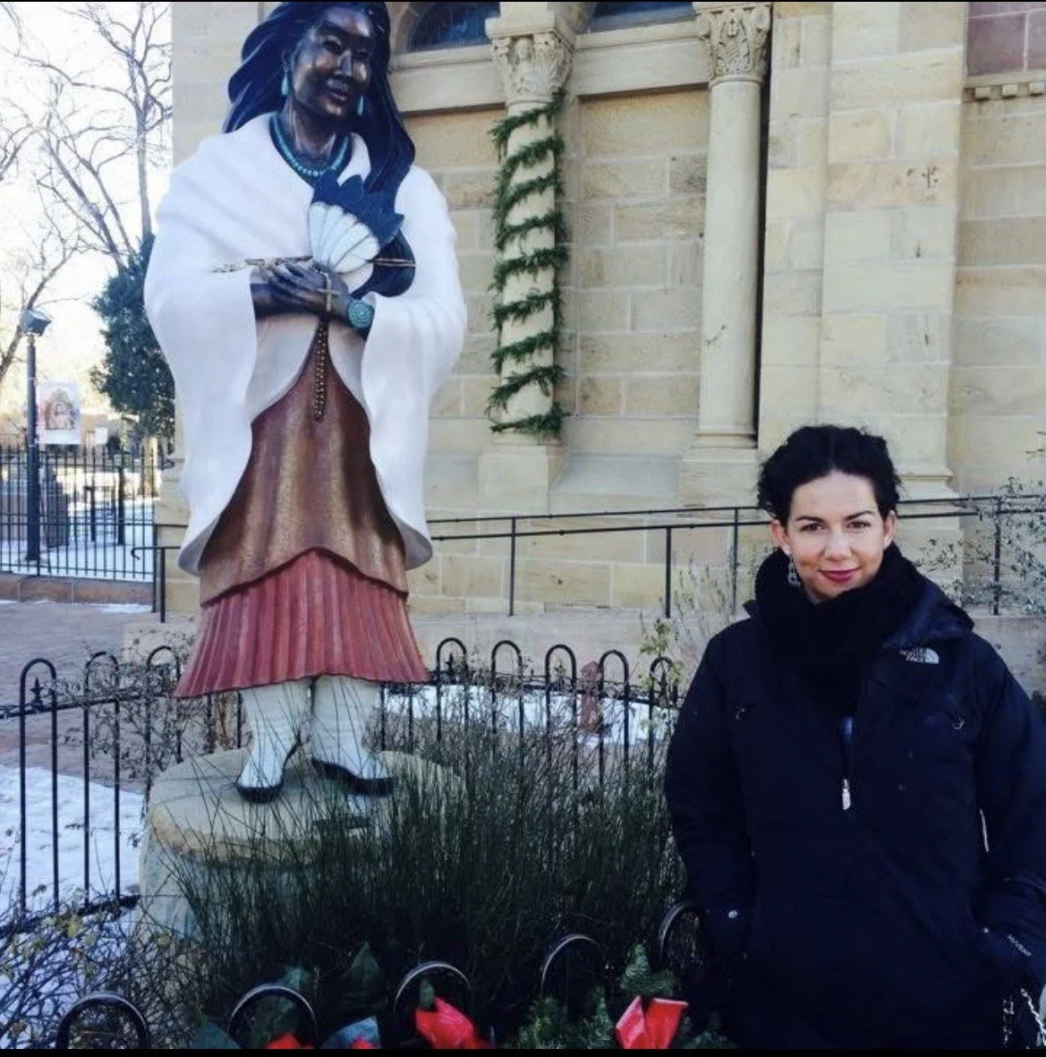 Christy Ford visiting Santa Fe beside a statue and historic stone building