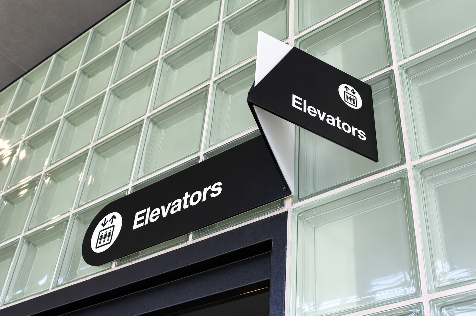 Modern Elevator Signs on Glass Block Wall.png