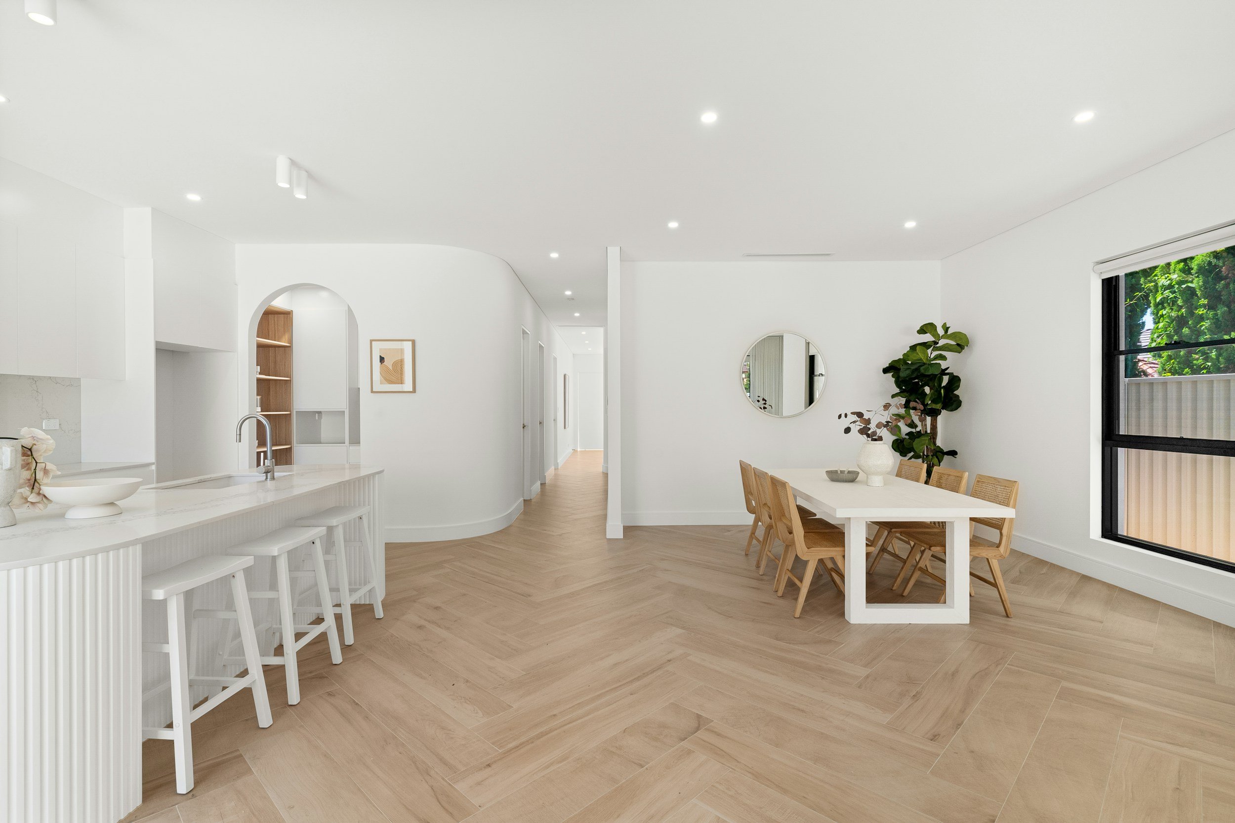 Bright, minimalist dining space finished as part of a cosmetic home renovation, featuring wooden furniture, white walls and natural light
