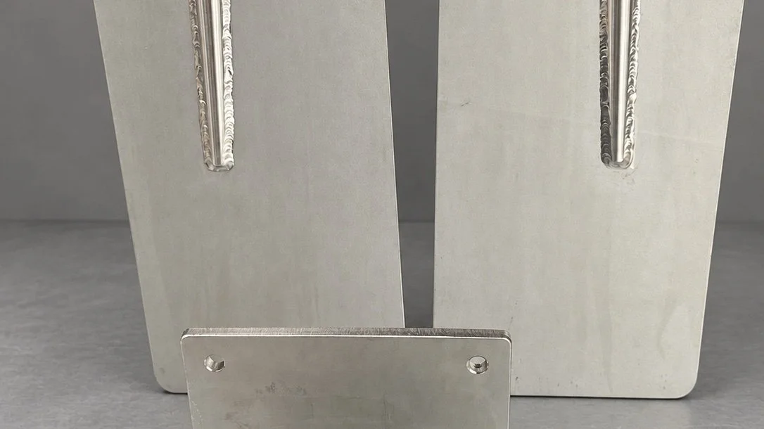 Close-up of metallic object with two vertical plates and a horizontal piece at the bottom, all with visible screw holes.
