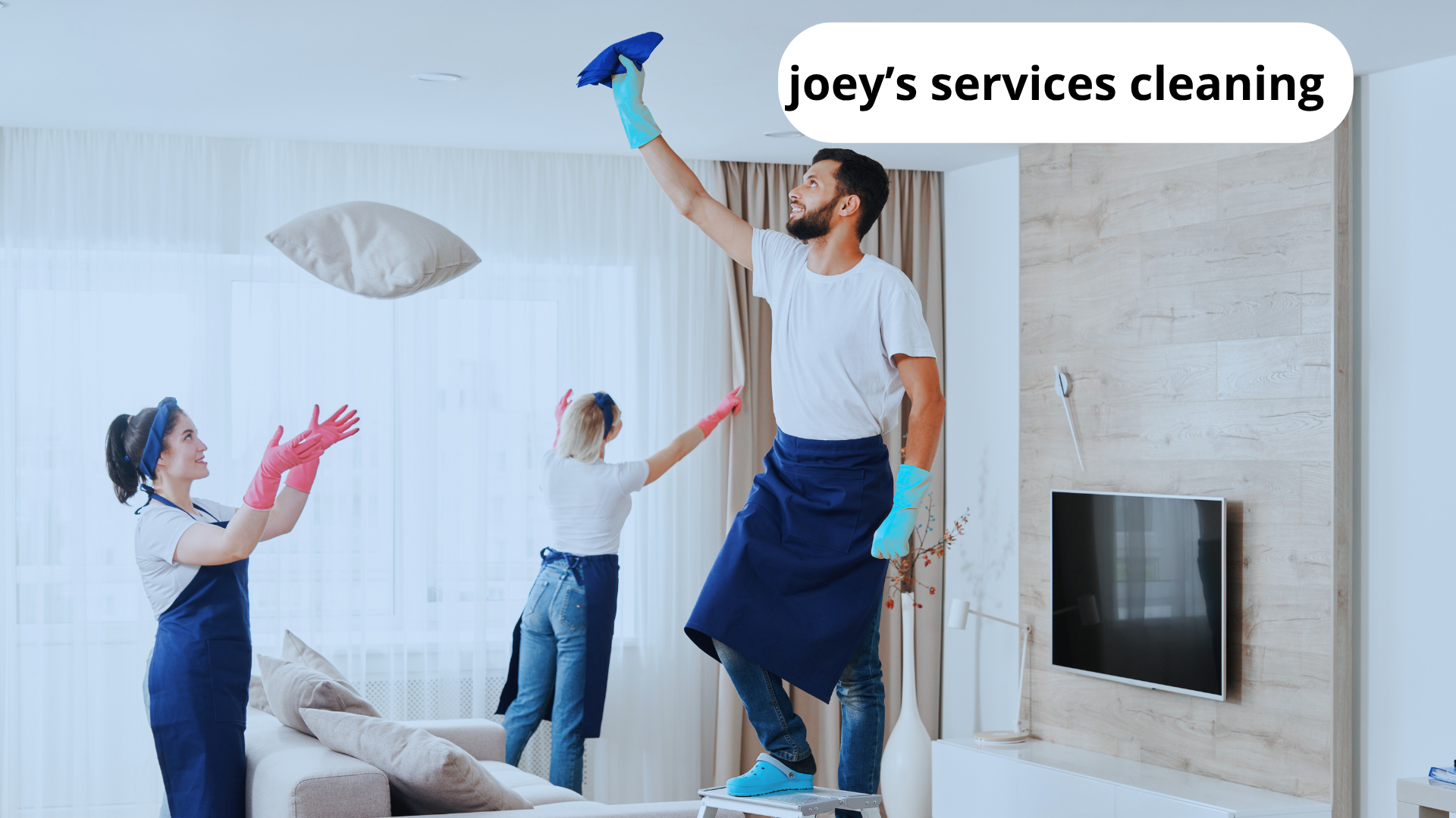 Group of people holding pillows and tossing them in the air in a living room during a cleaning service.