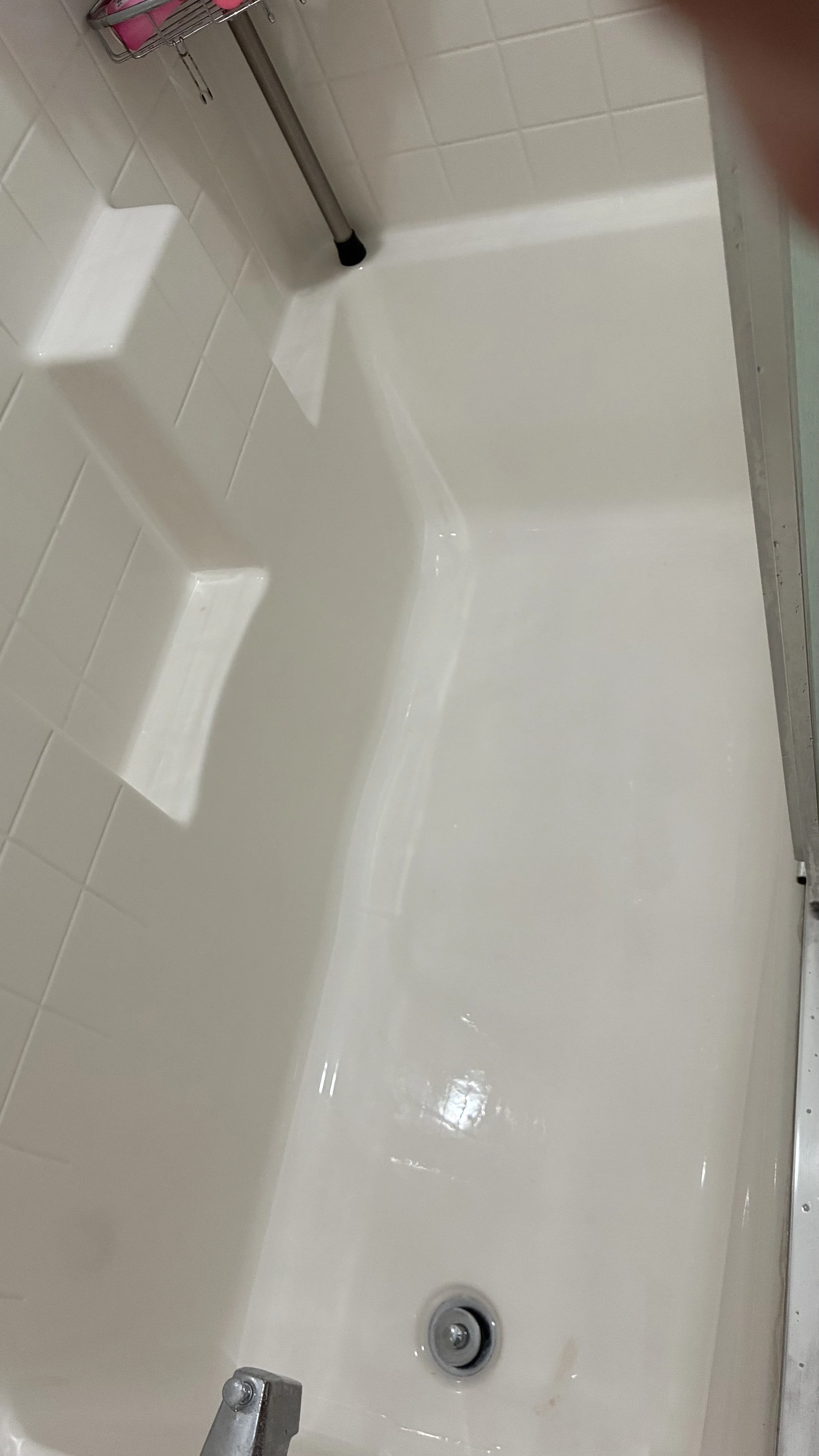 Empty bathroom shower with white tiles, built-in soap dish, and metal fixtures.