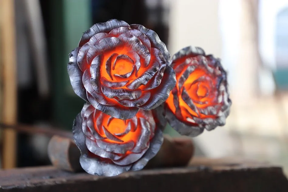 Decorative metal roses with glowing lights inside, placed on a wooden surface.