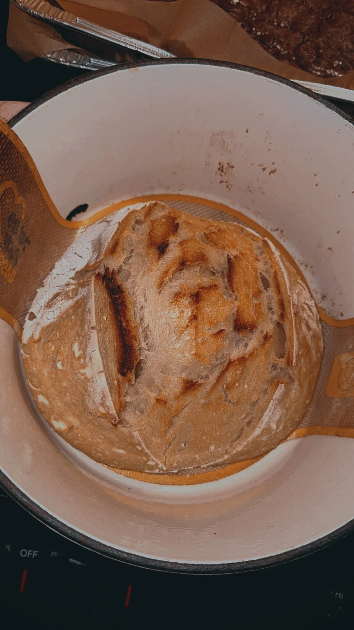 Empty skillet with burnt remnants of food and flour inside, placed on a black stovetop with some drawers and baking trays in the background.