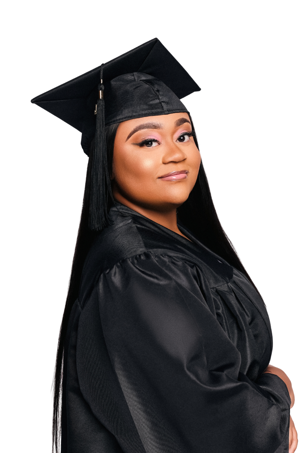 Young woman in a black graduation gown and cap, smiling slightly, facing sideways with her arms crossed.