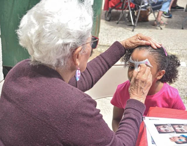 Young girl having her face painted during a family-friendly creative arts experience with FAM Entertainment Theater Company.