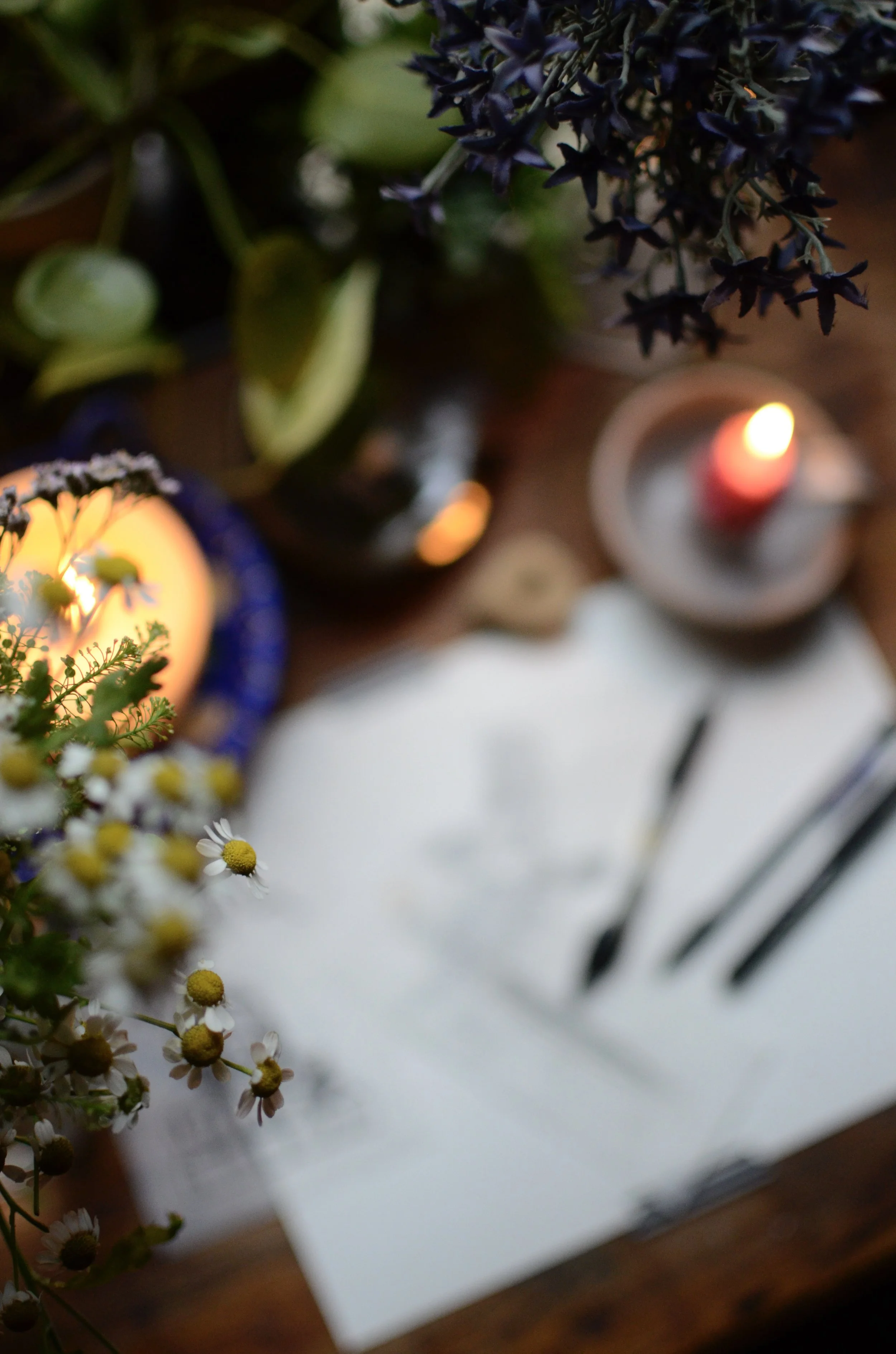 Close-up view of a table with small candles, flowers, and greenery, creating a cozy and decorative setting.