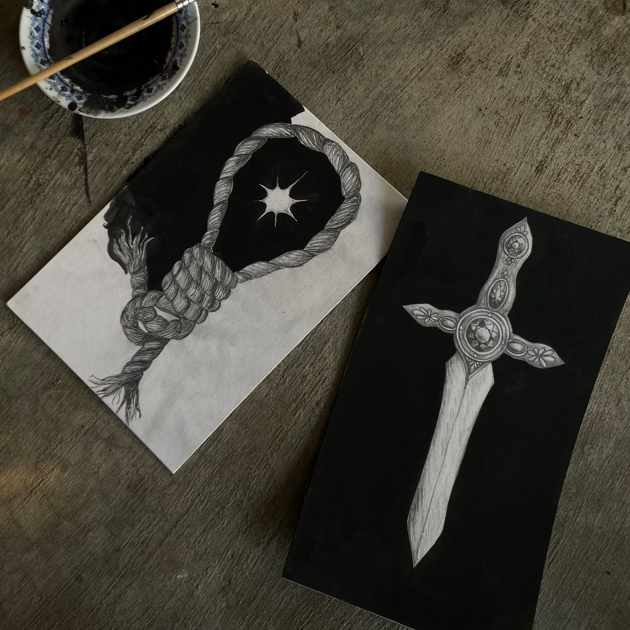 Black and white drawing of a diamond enclosed in a twisting rope, with a black background. There is also an art piece with a diamond-shaped design containing a metallic, circular object on a black background.