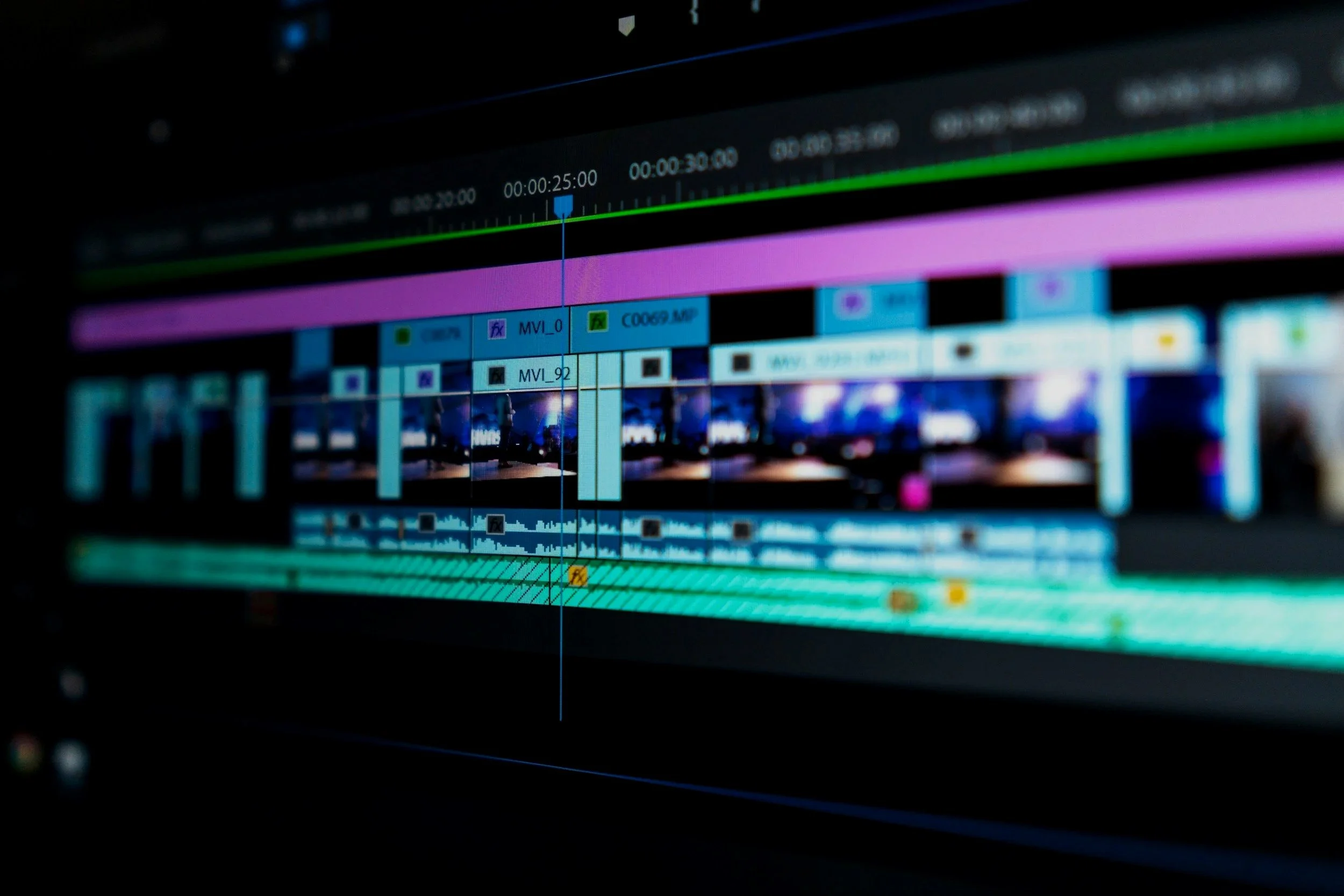 Close-up of a non-linear editing (NLE) timeline with colored video and audio clips on a dark background.