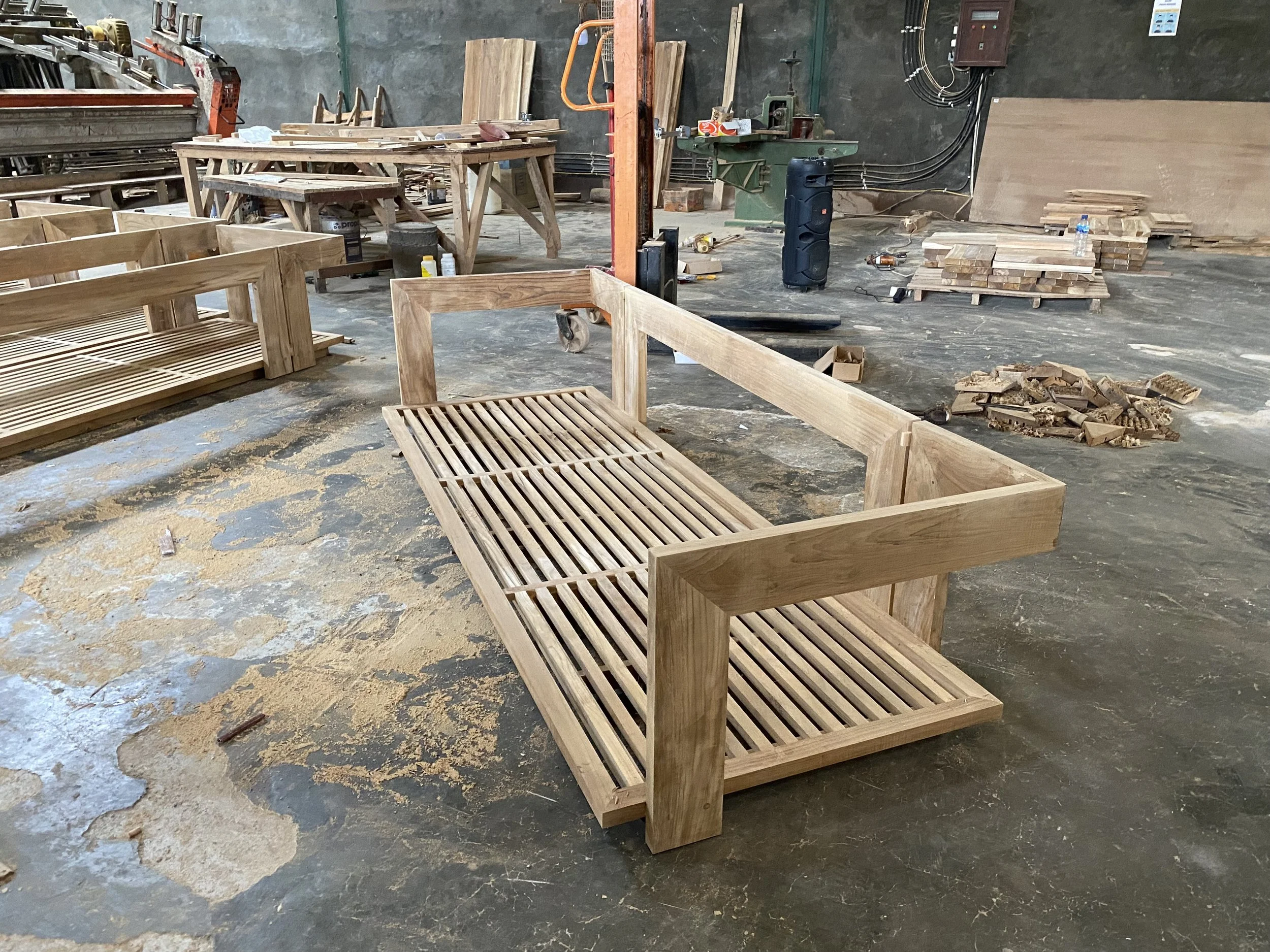 Wooden furniture pieces in a woodworking shop, with tools and wood in the background.