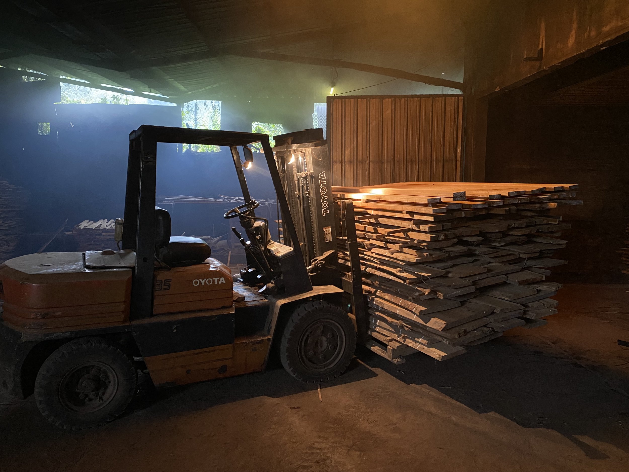 A forklift truck carrying a large stack of teak wooden planks inside a dry kiln oven. Teak Furniture Jepara, wholesale Indonesian teak furniture, custom outdoor teak furniture manufacturer, Jepara teak furniture supplier. 
