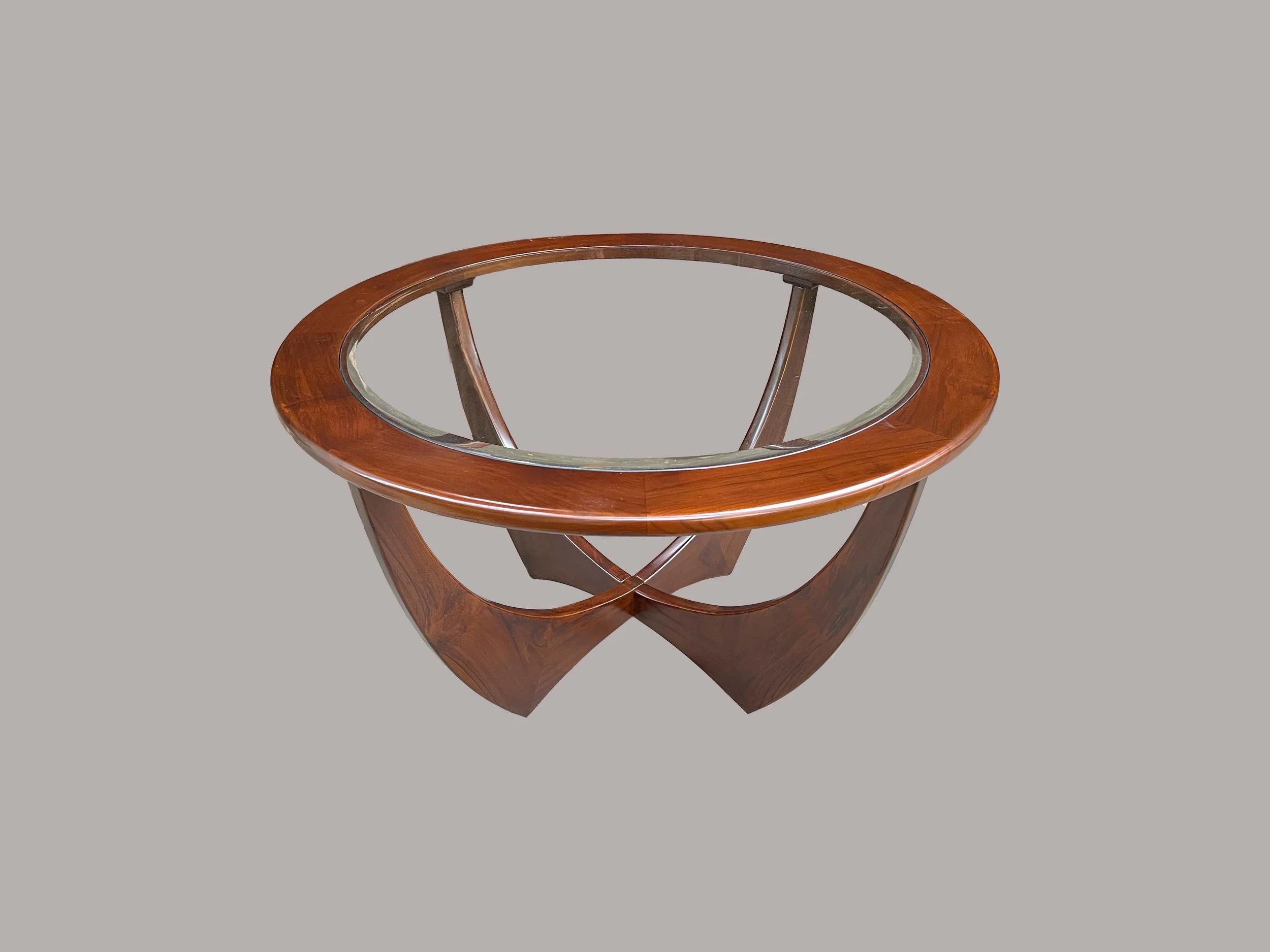 A round wooden table with a glass top and a unique curved base.