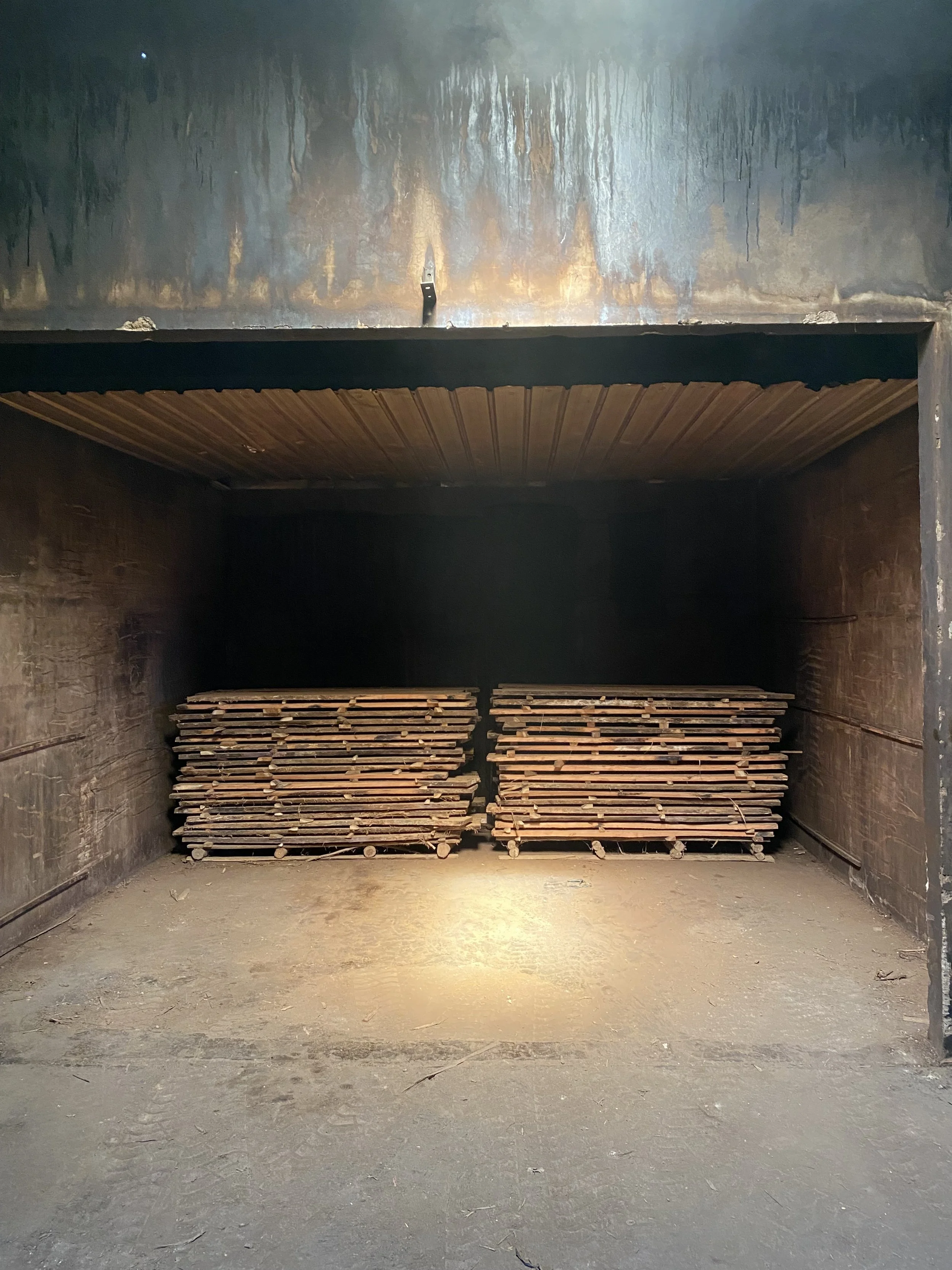 Industrial kiln with teak wooden pallets stacked at the bottom and a metal surface at the top. Teak Furniture Jepara, wholesale Indonesian teak furniture, custom outdoor teak furniture manufacturer, Jepara teak furniture supplier. 