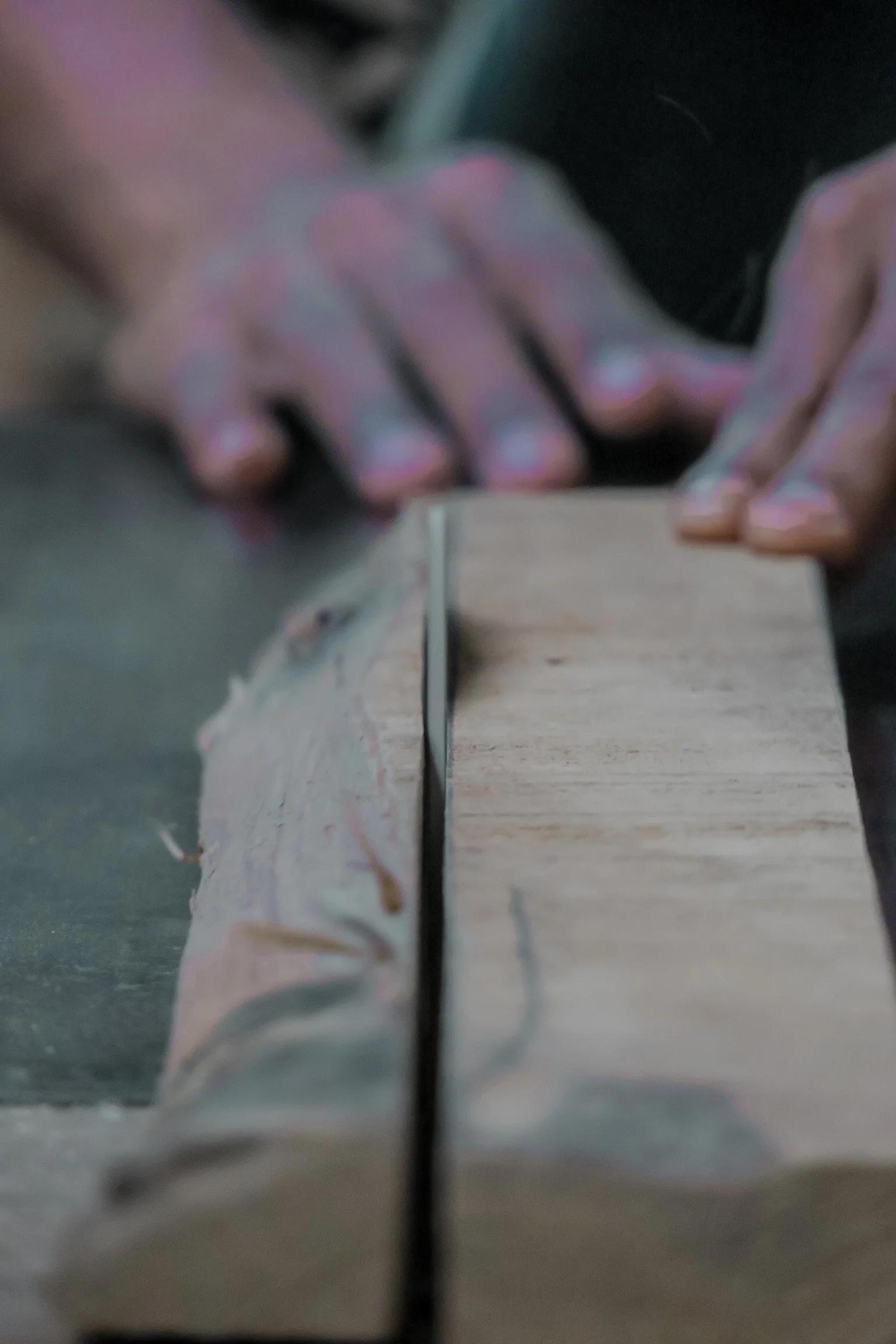 Close-up of a handsaw cutting through a piece of teak wood on a workbench. Teak Furniture Jepara, wholesale Indonesian teak furniture, custom outdoor teak furniture manufacturer, Jepara teak furniture supplier. 