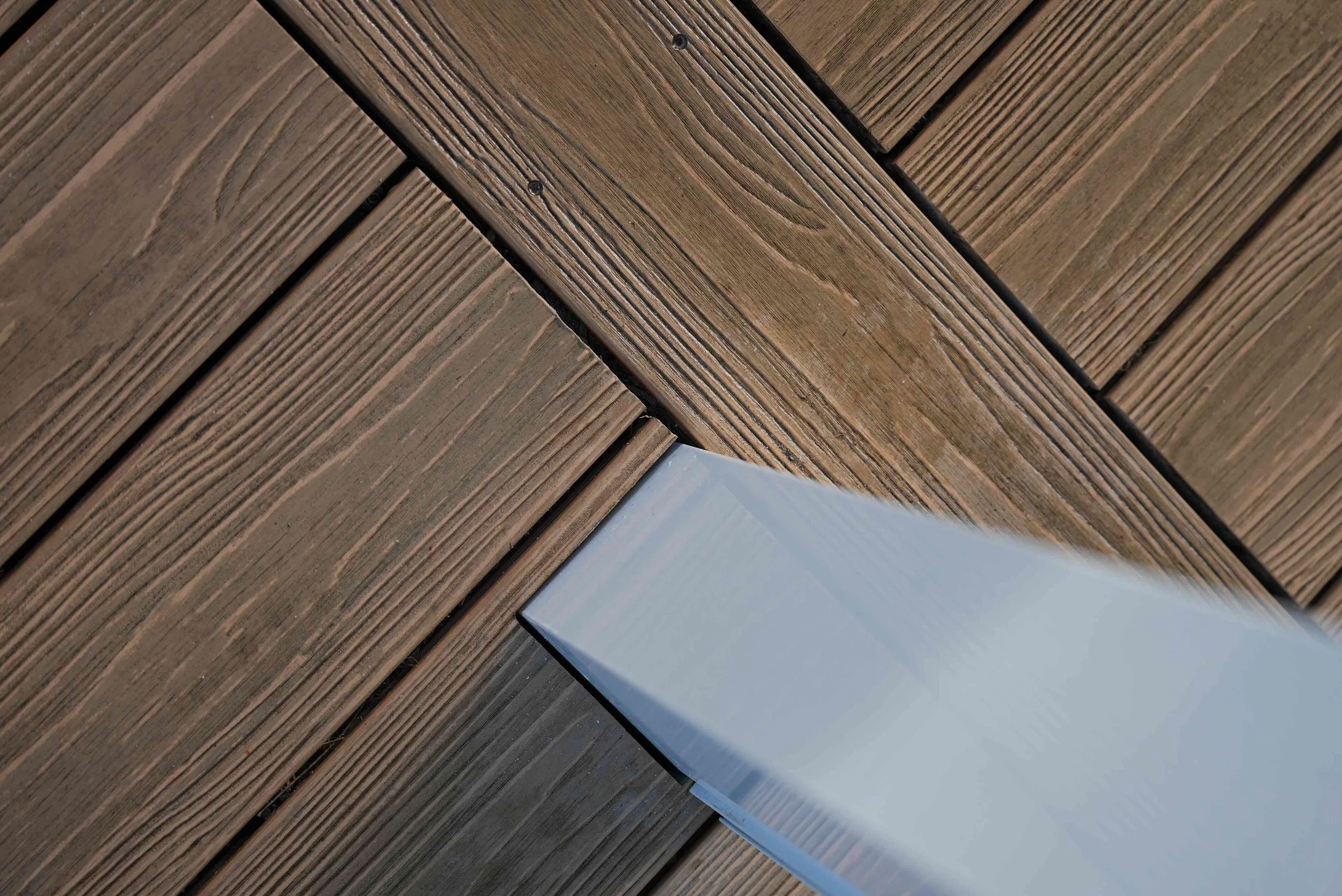 Close-up of a wooden deck with a white rectangular tile or piece in the corner