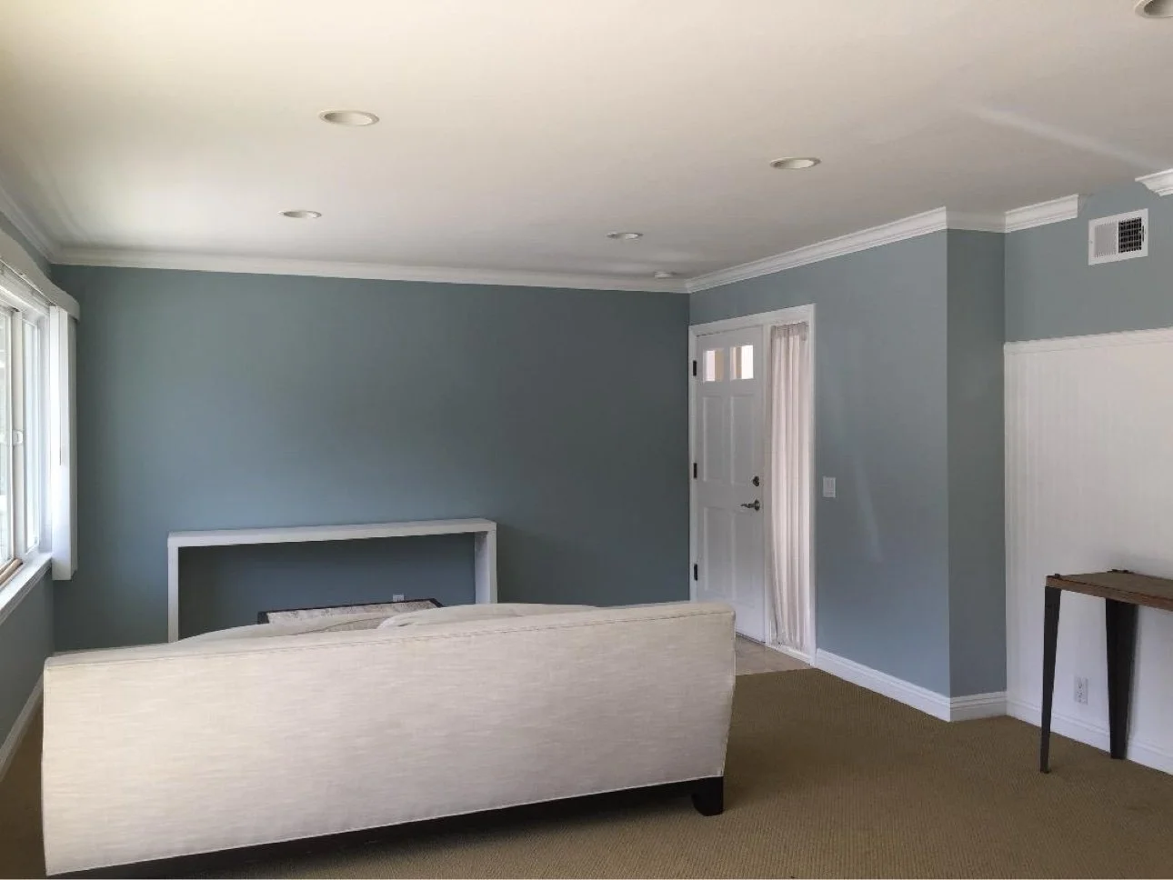 Interior repaint — living room with blue-gray walls, white trim, and cream sofa