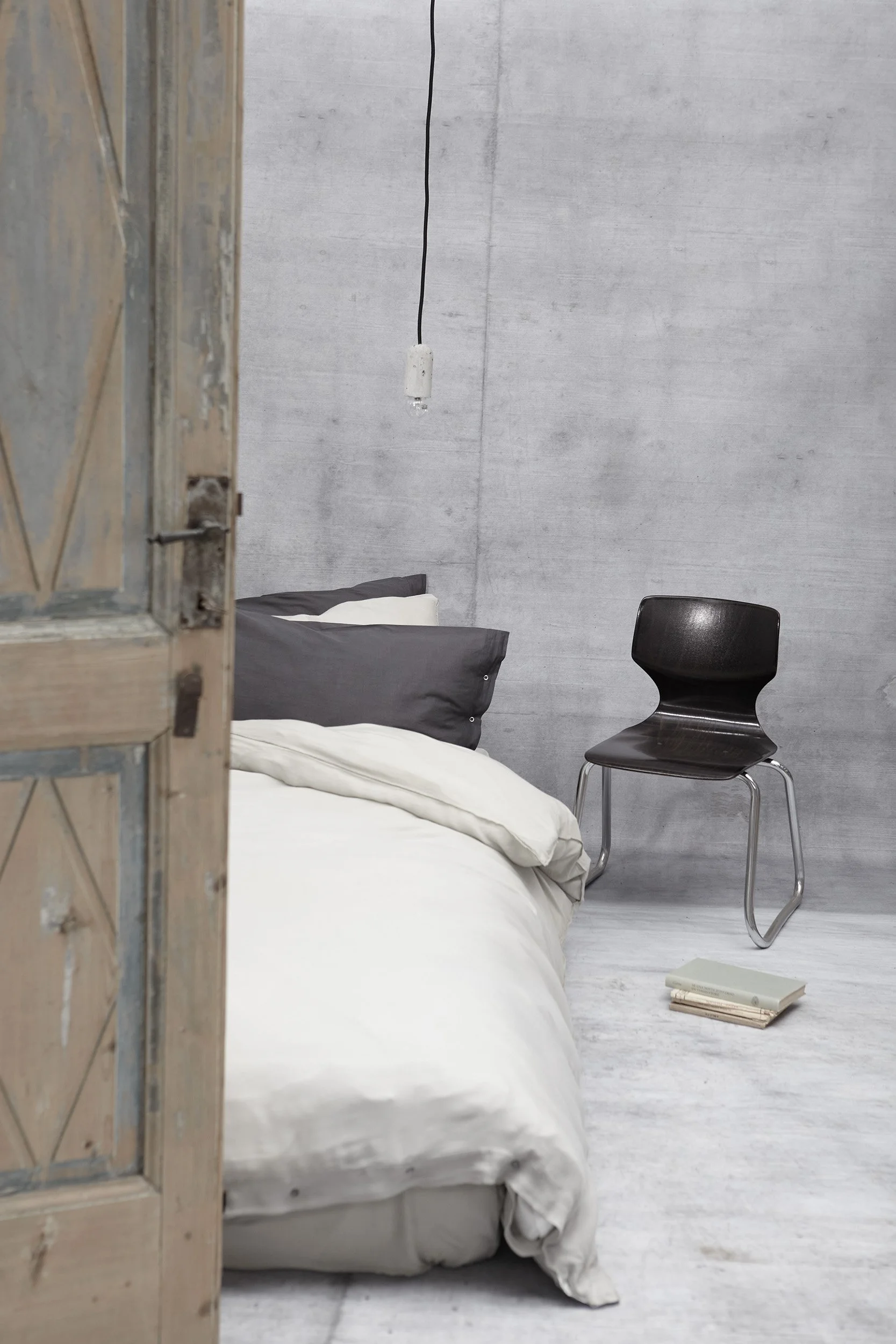 Minimal bedroom with white linen bedding and concrete walls