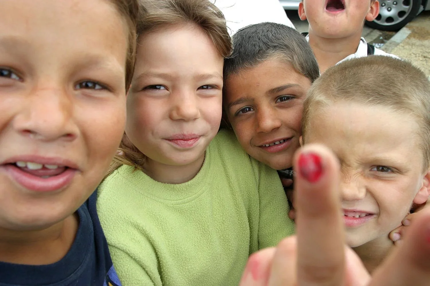 Four children crowded into the frame, one pointing a painted finger at the lens.