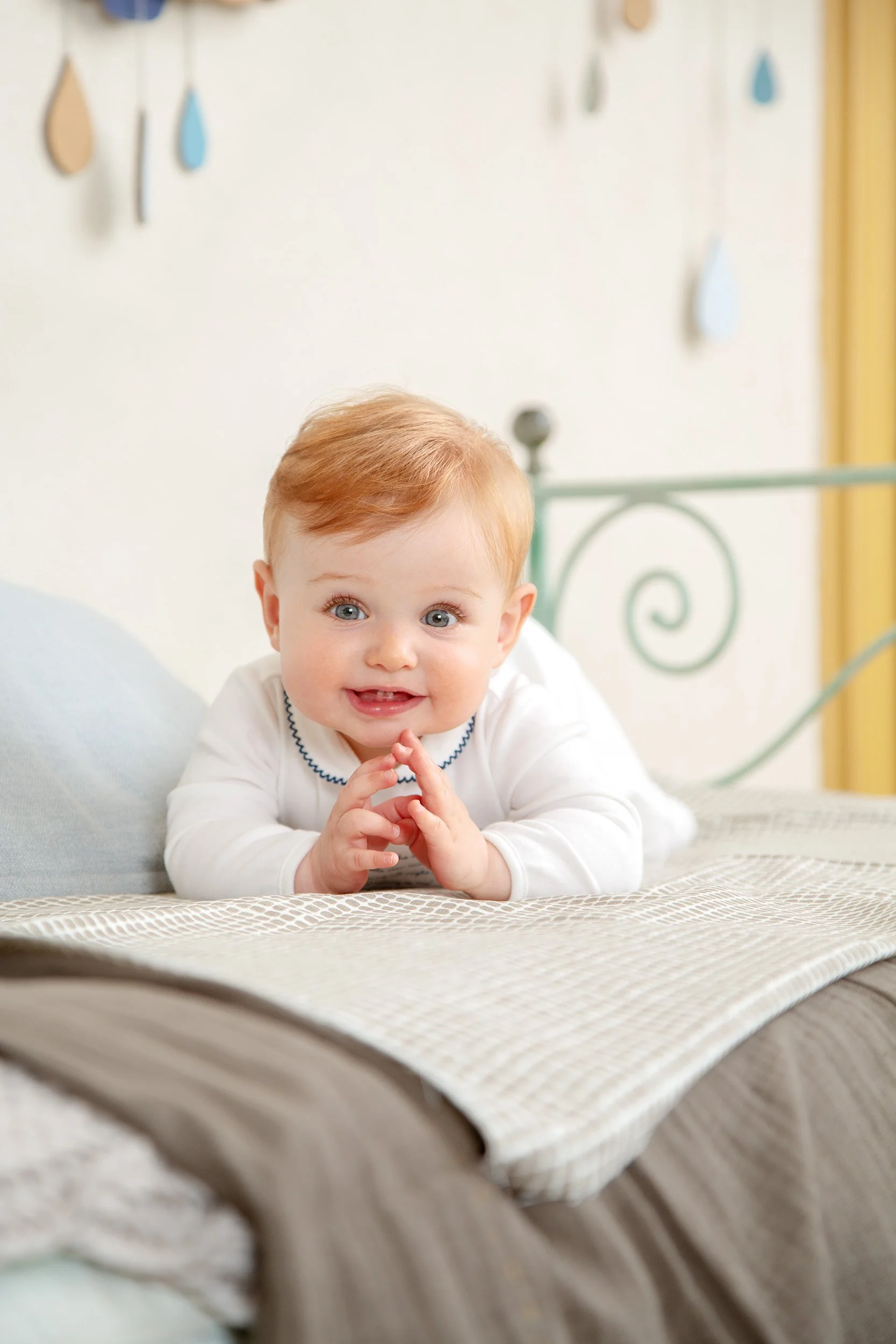 Prénatal — newborn on a bed, hands together, white cotton.