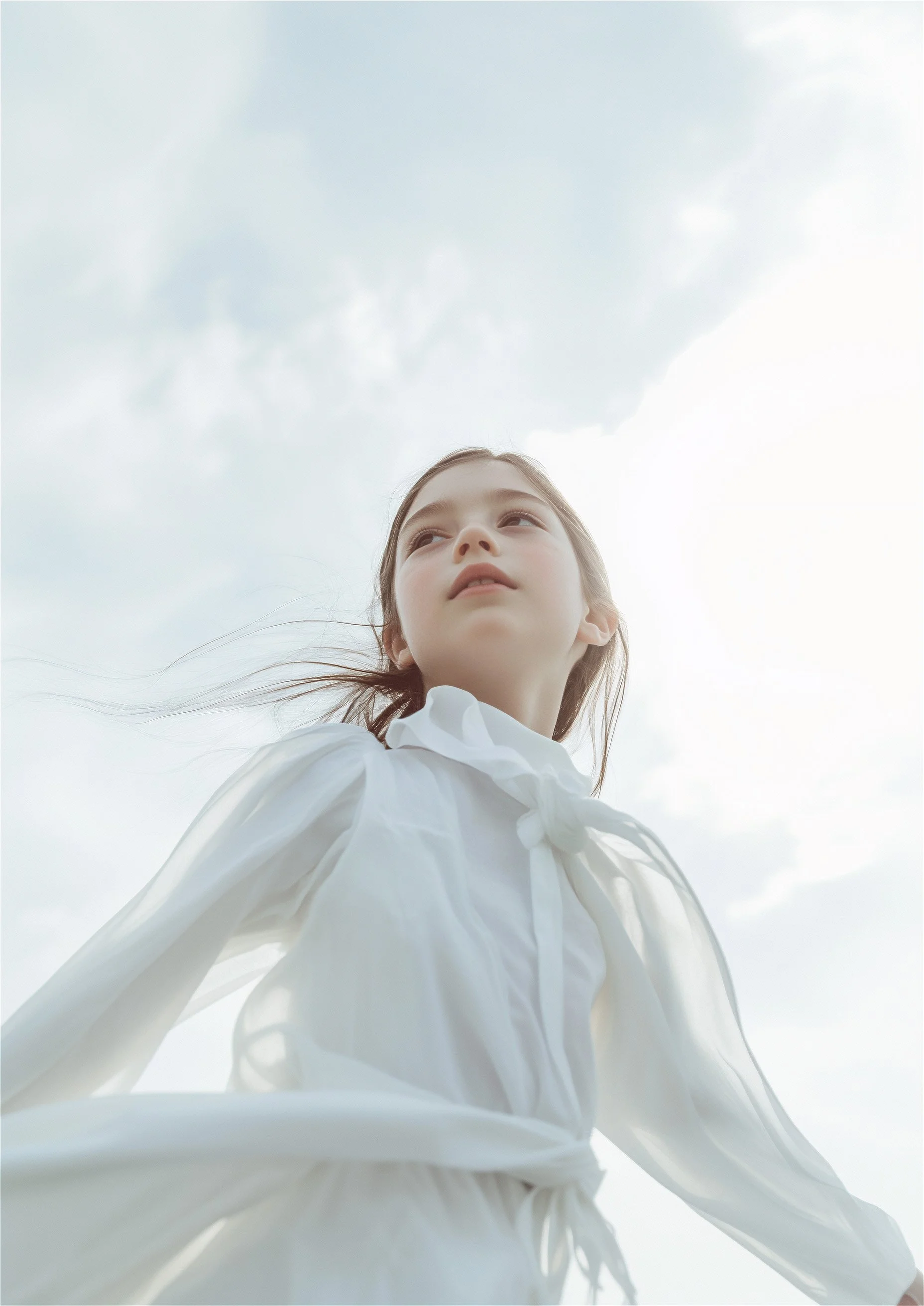 Girl in a white dress, sleeves lifted by the wind, against open sky. AI-generated image.
