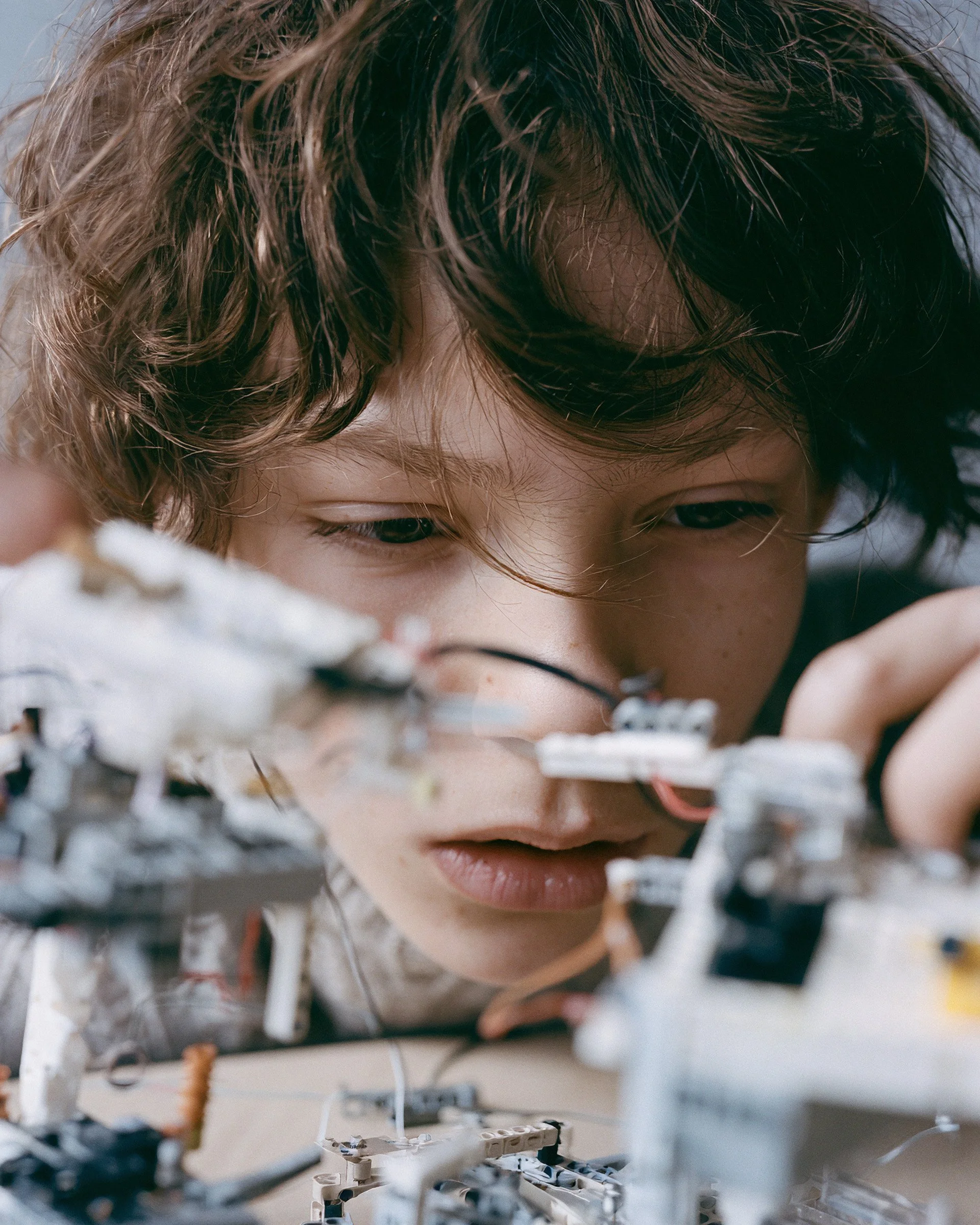 Boy concentrating on a Lego construction, shallow focus. AI-generated image.