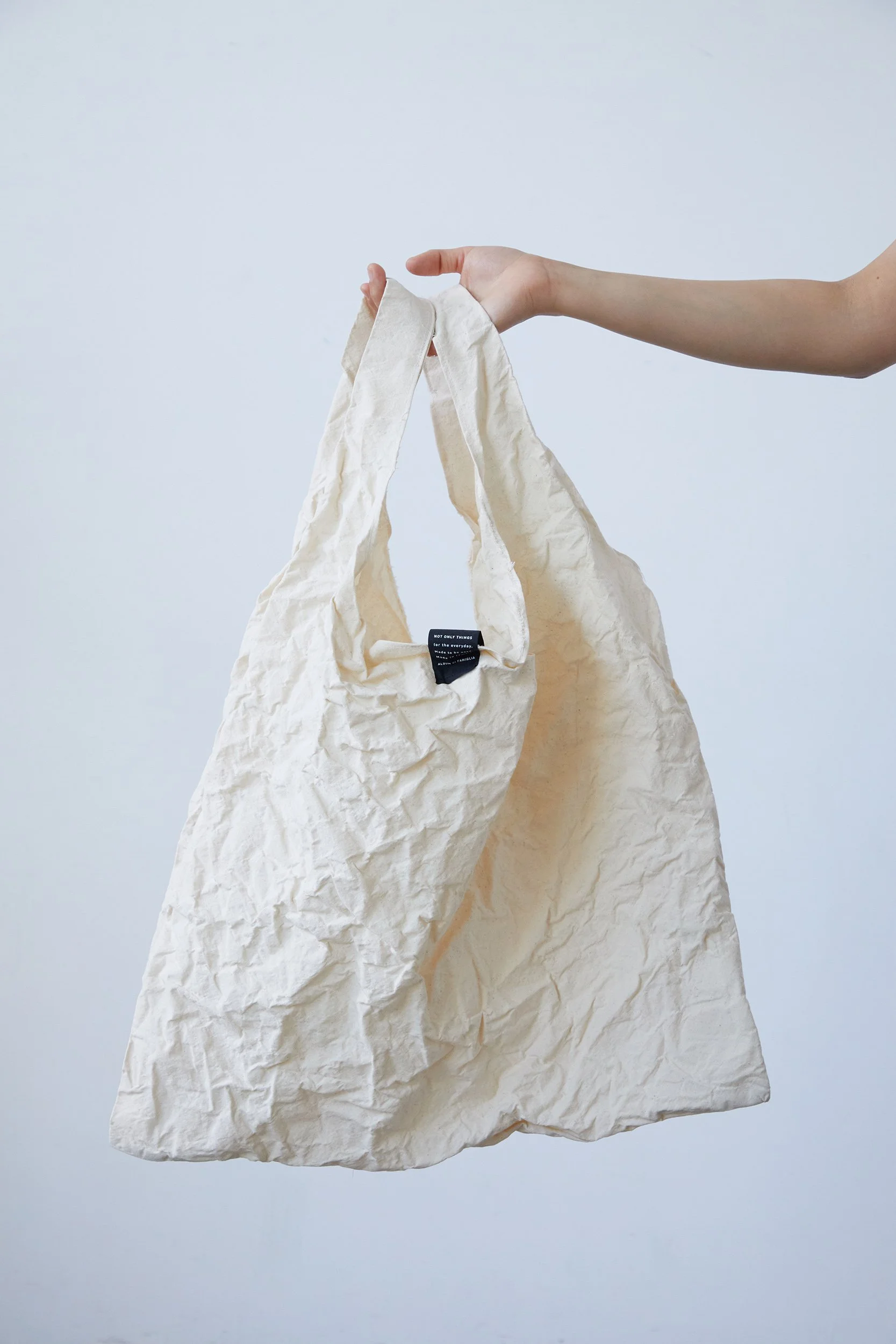 Hand holding a crumpled natural cotton tote bag