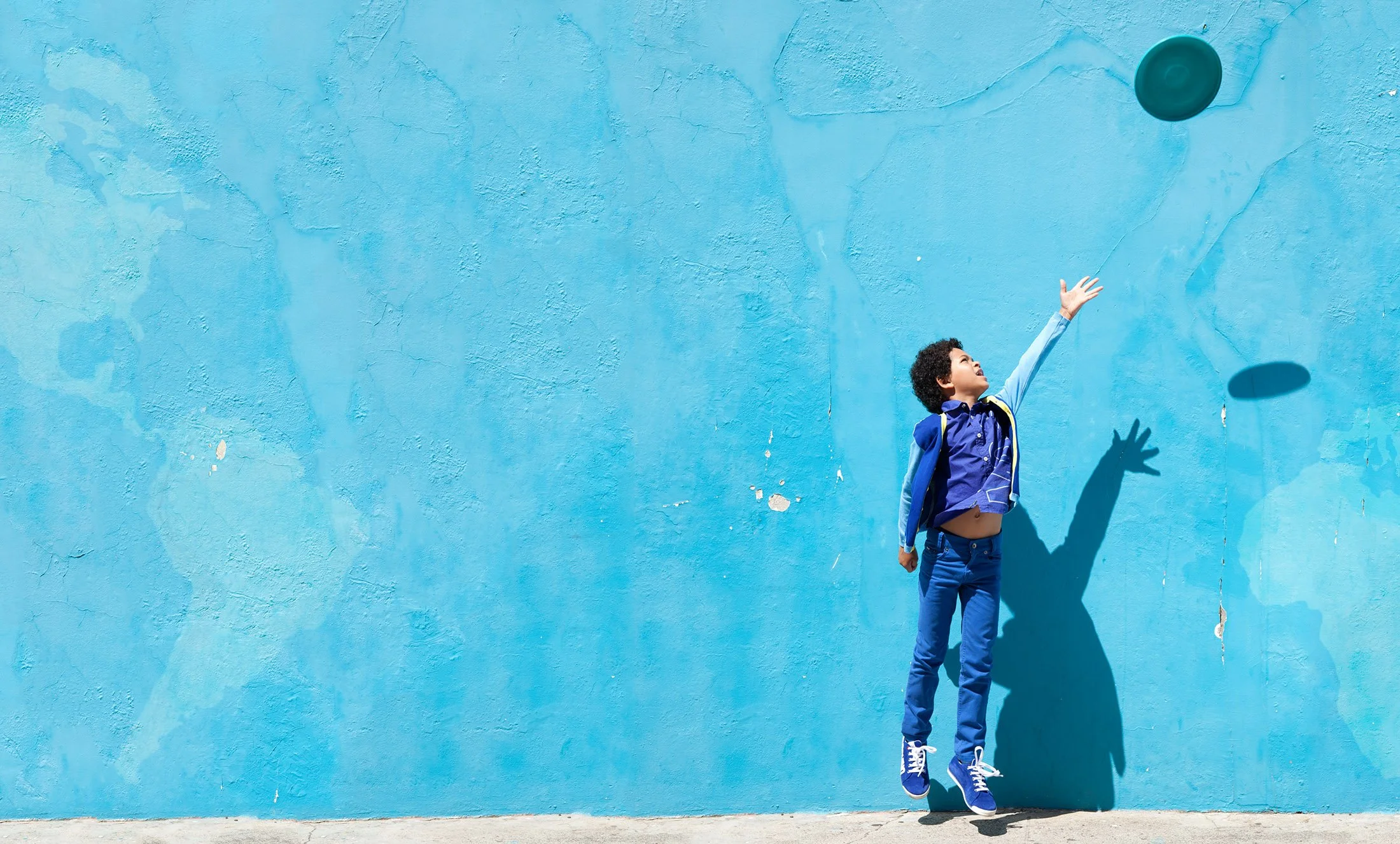 Style Piccoli editorial — a kids throwing a frisbee against a turquoise wall in Bo-Kaap, Cape Town.