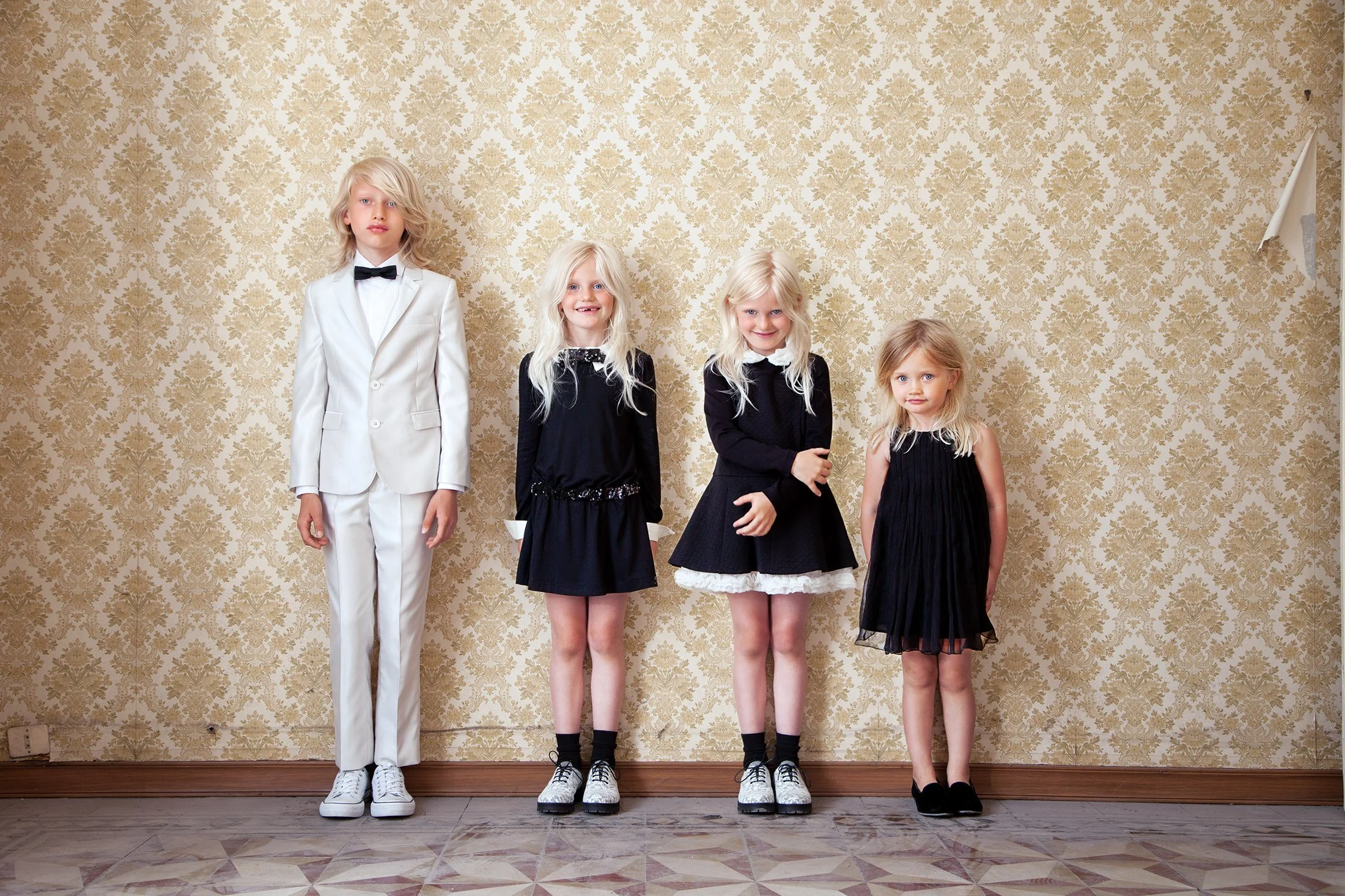 Style Piccoli— brother and sisters lined up against patterned wallpaper.