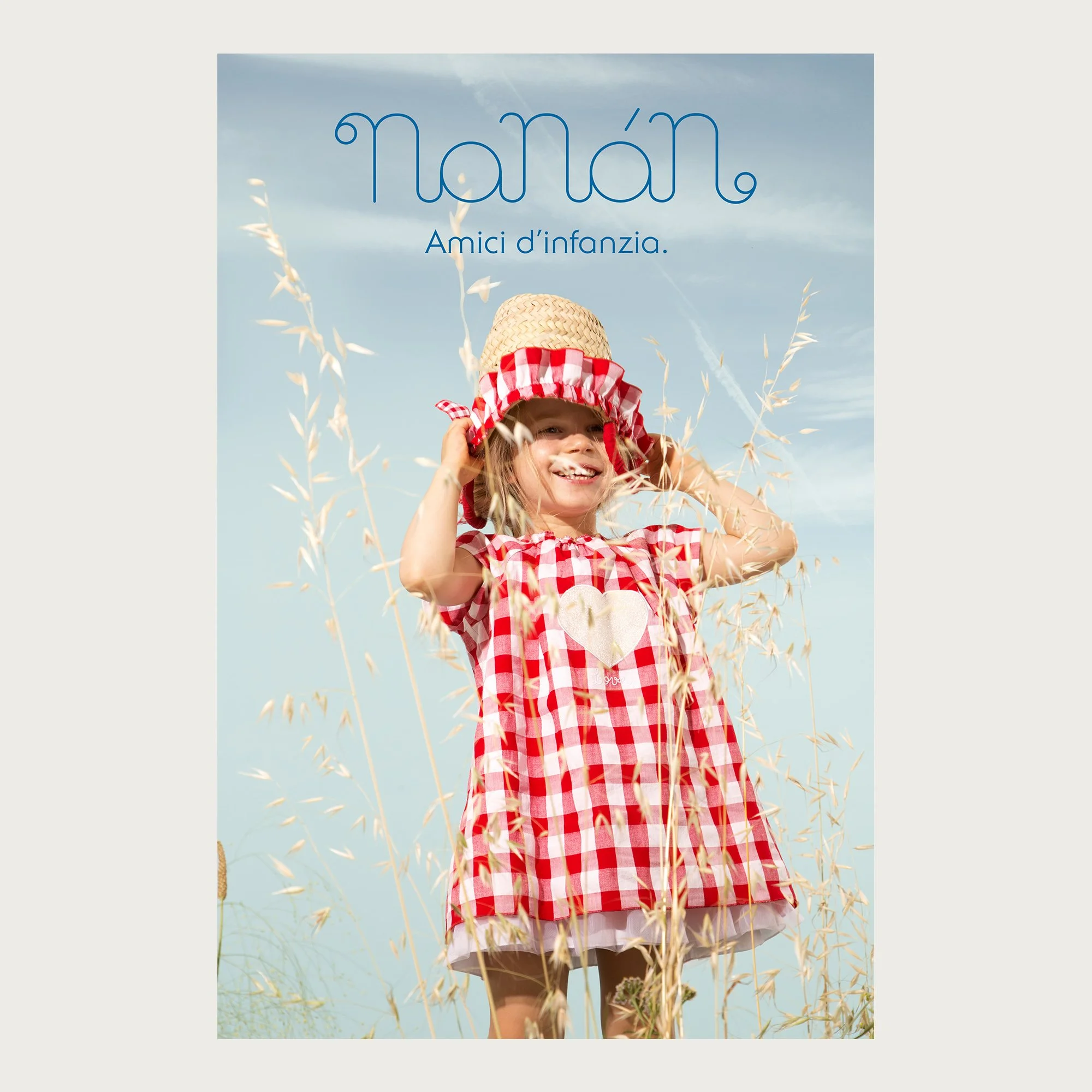 Red gingham dress and straw bonnet, girl in an oat field against the sky — Nanán campaign
