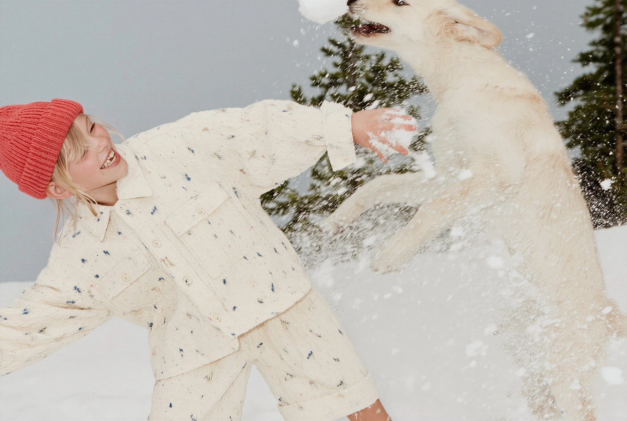 Girl in a red beanie playing in fresh snow with a white dog. AI-generated image.