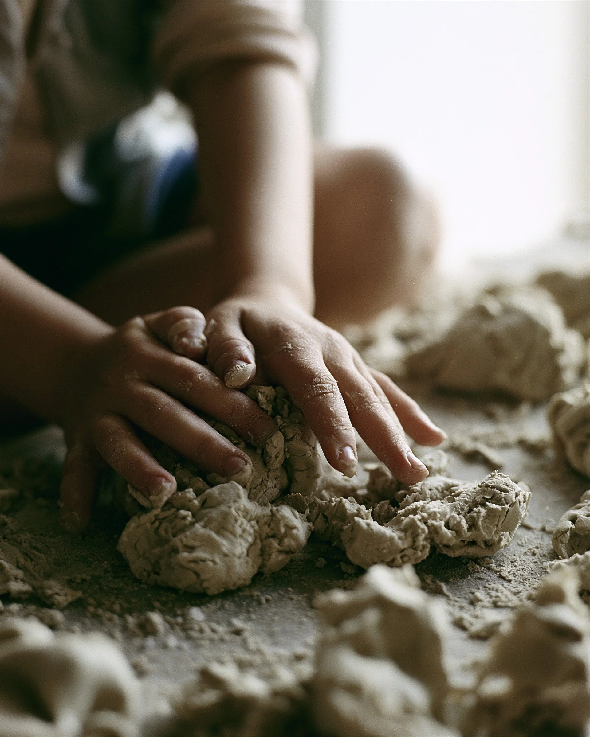 Children’s hands working wet clay, close. AI-generated image.