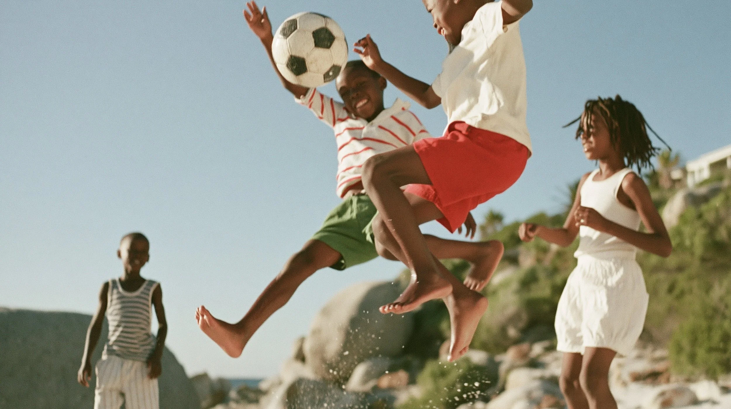 Children playing football on a hillside, the ball caught mid-air. AI-generated image.