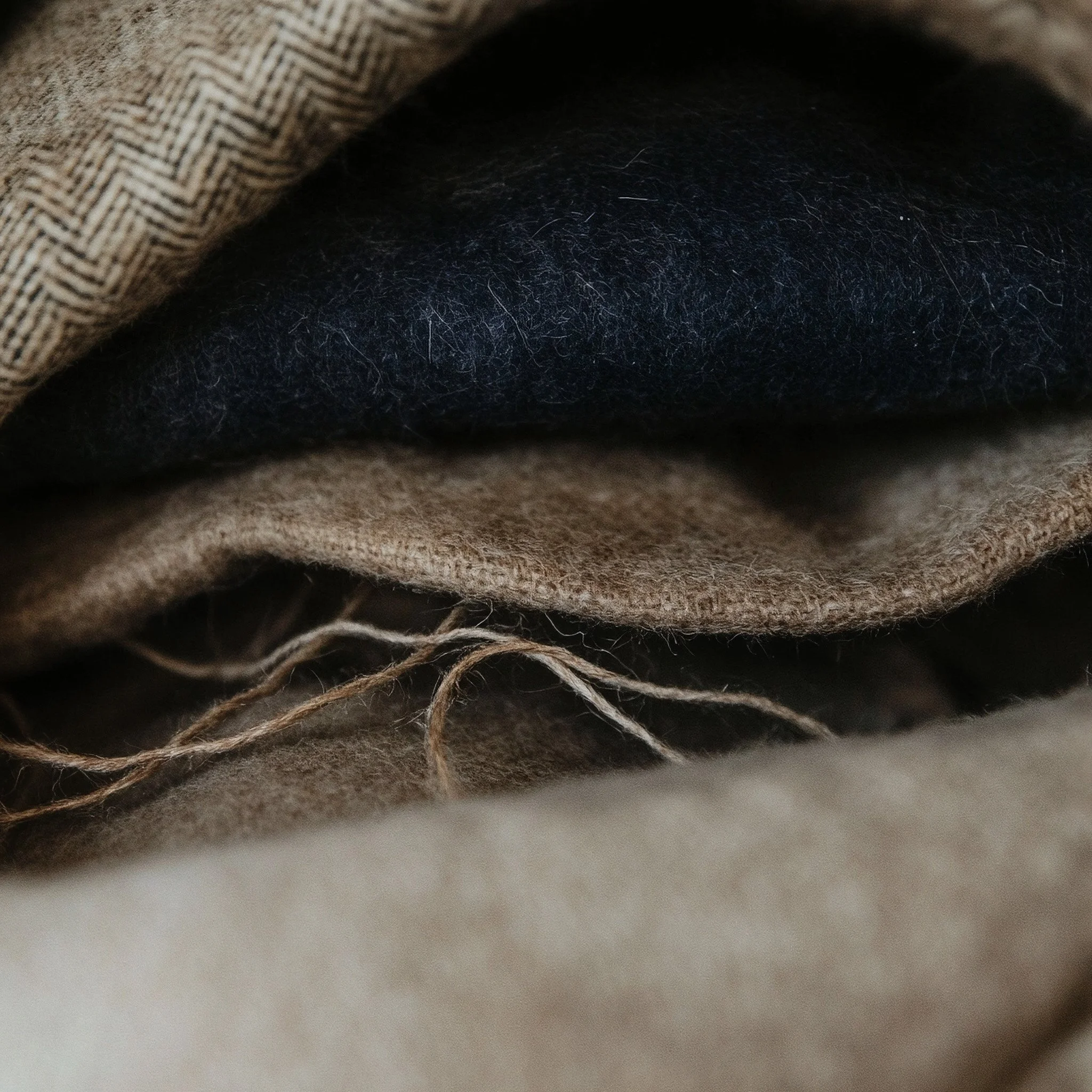 Folded wool blankets in brown, black and beige.